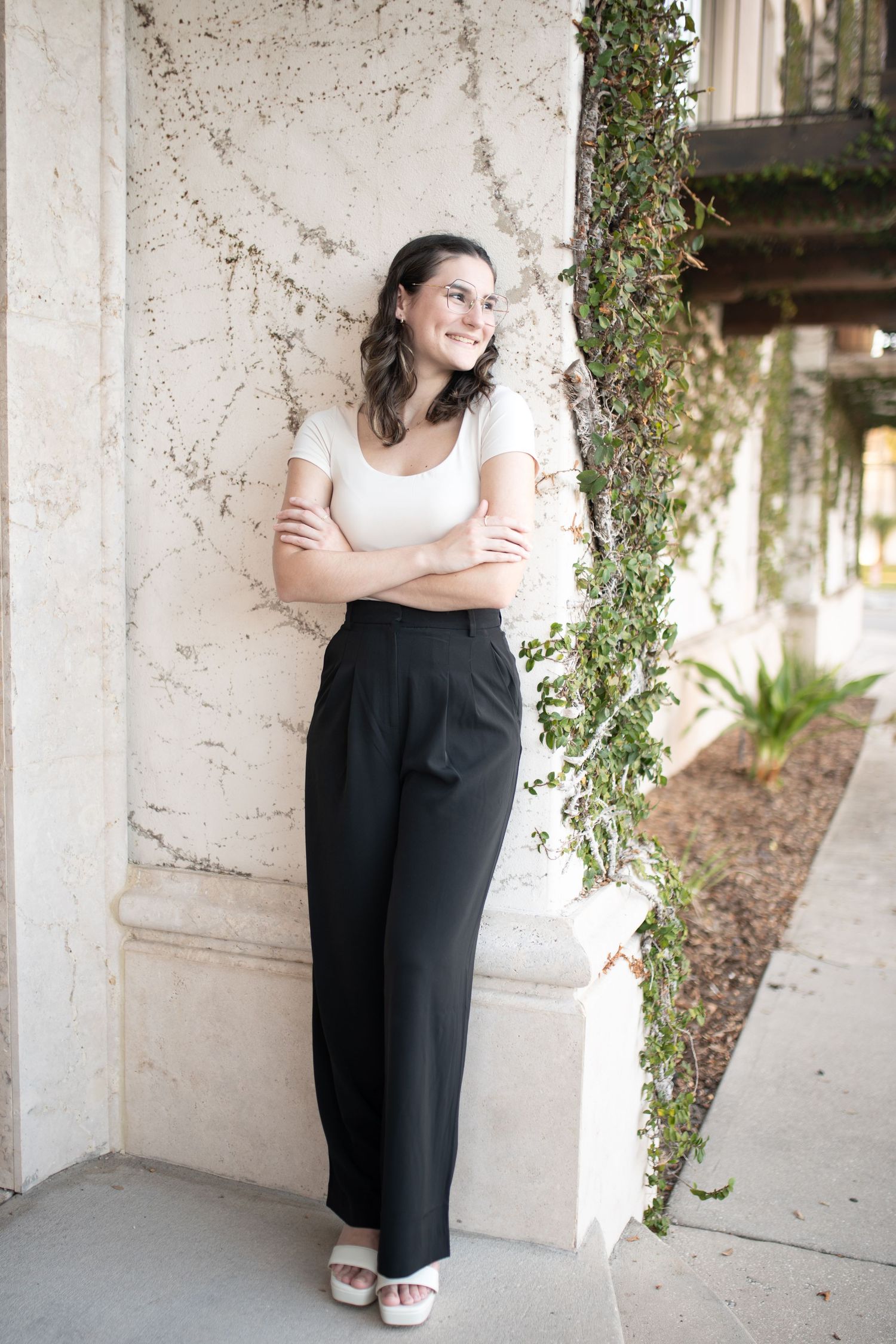 Portrait session against white textured wall with ivy featuring casual black and white outfit.