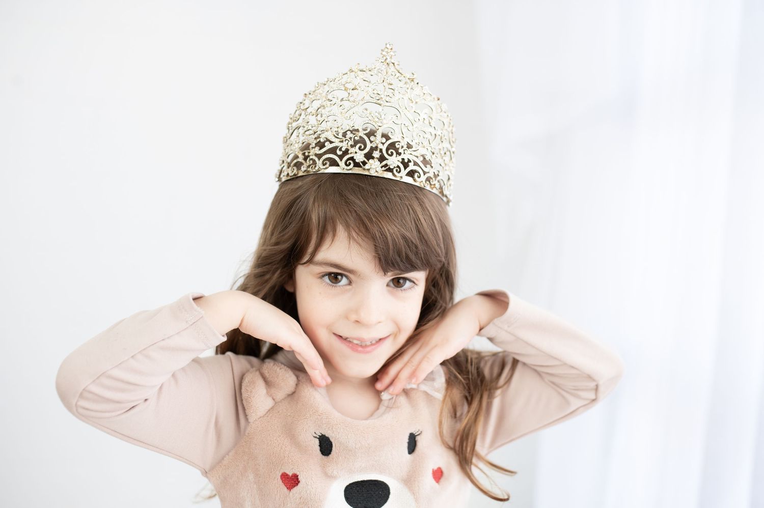 A series of four photos showing someone wearing a sparkly crown and making playful poses against a white background.