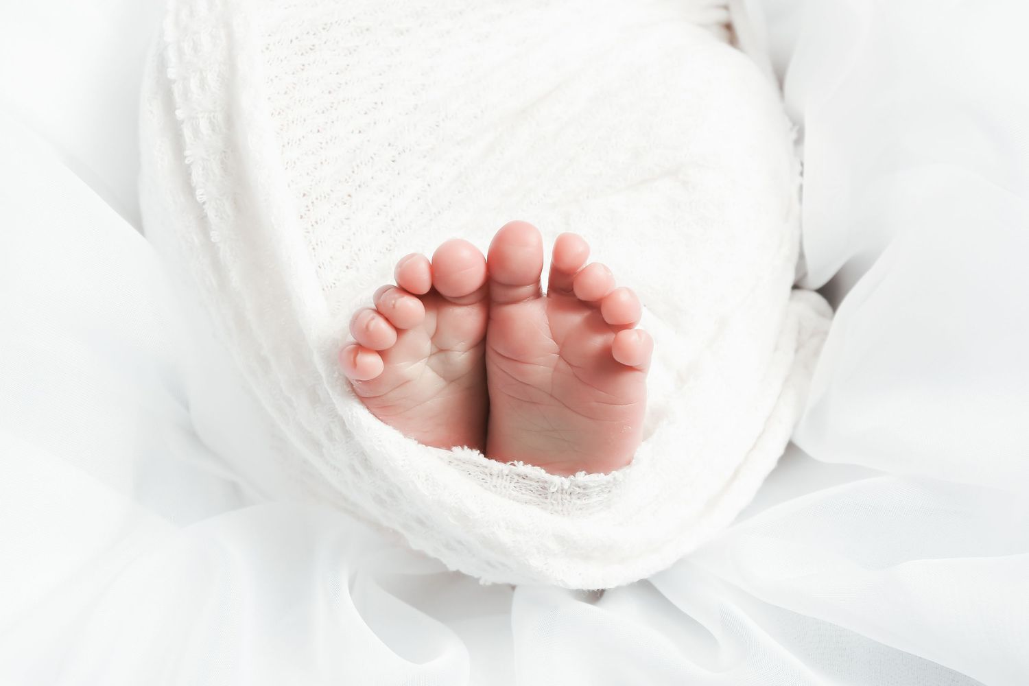 Close-up of tiny baby feet wrapped in white fabric.