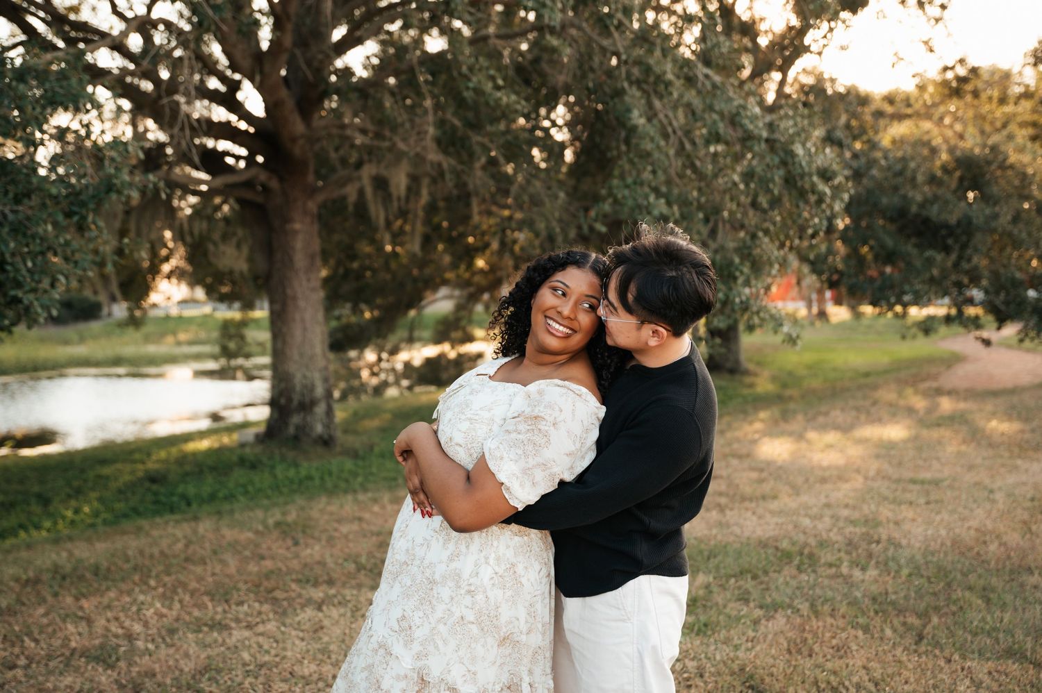A couple shares a romantic moment outdoors during a sunset wedding photo session in a rustic park setting.