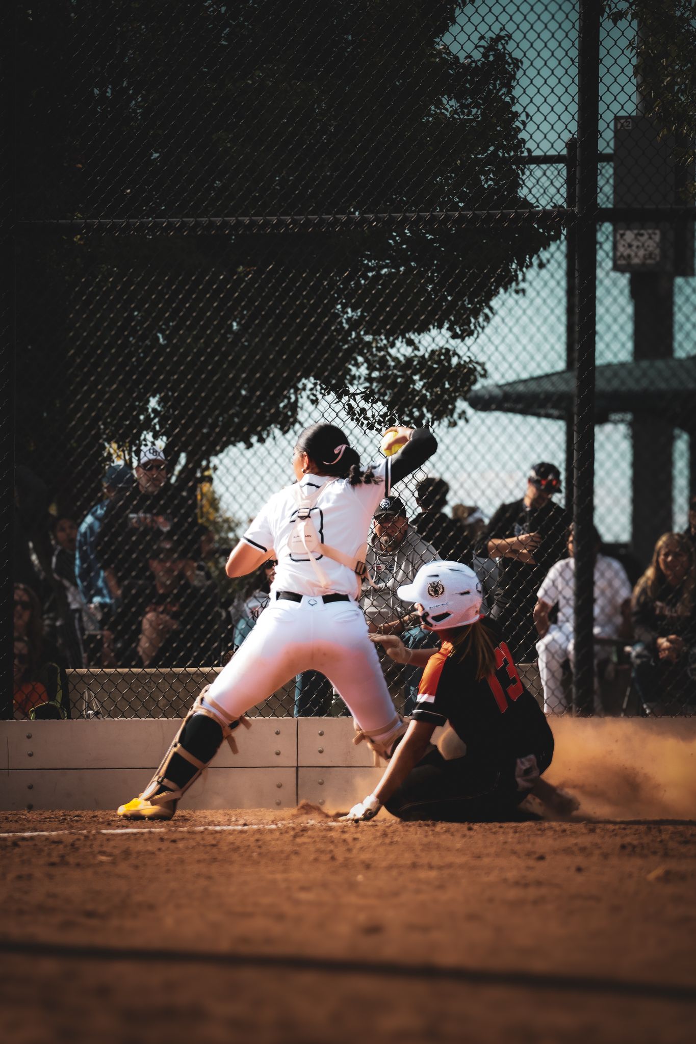 Baseball players in white uniforms perform a sliding play sequence at home plate during a game.