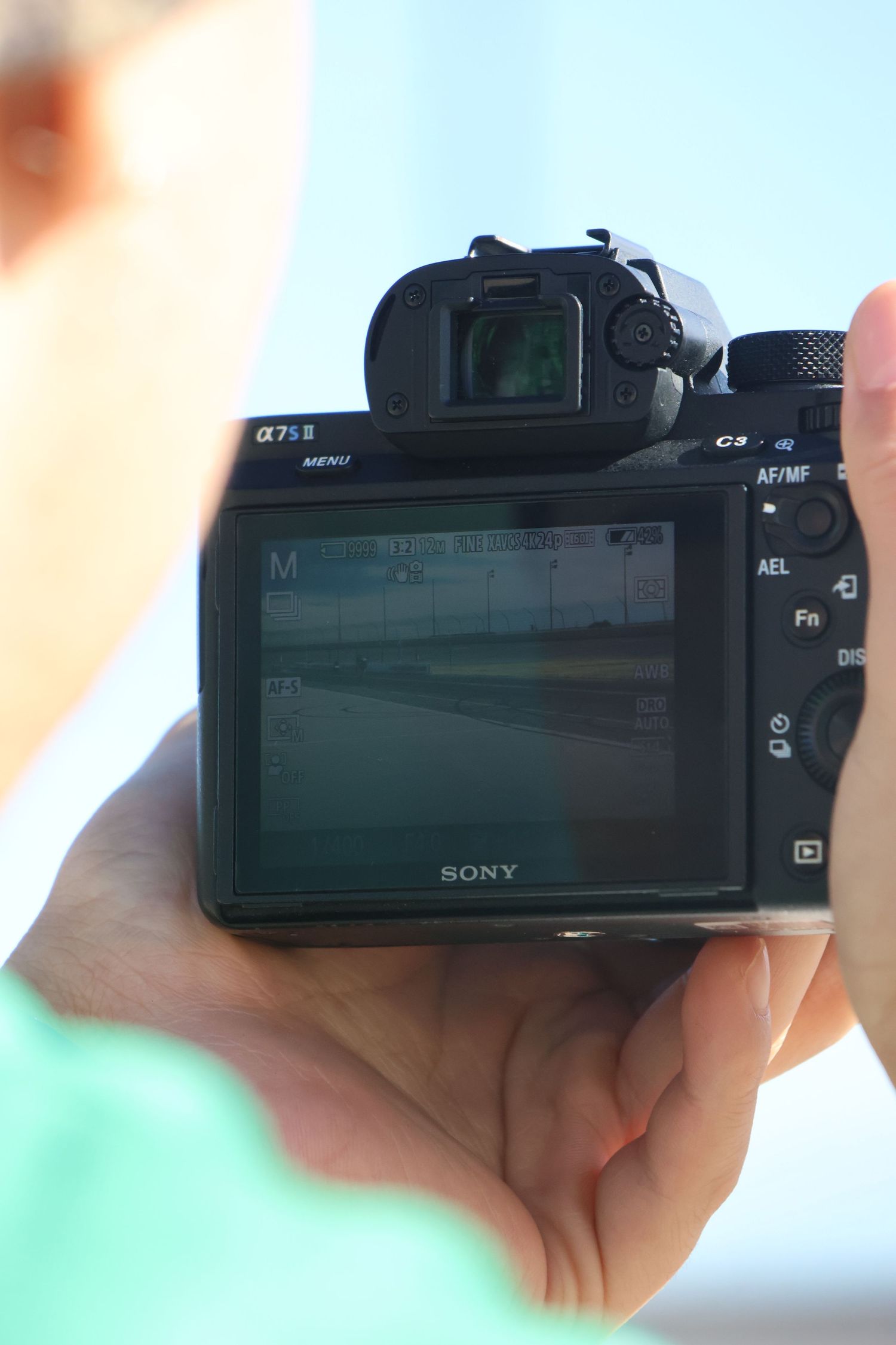 Close-up view of a Sony digital camera LCD screen display being held in someone's hands.