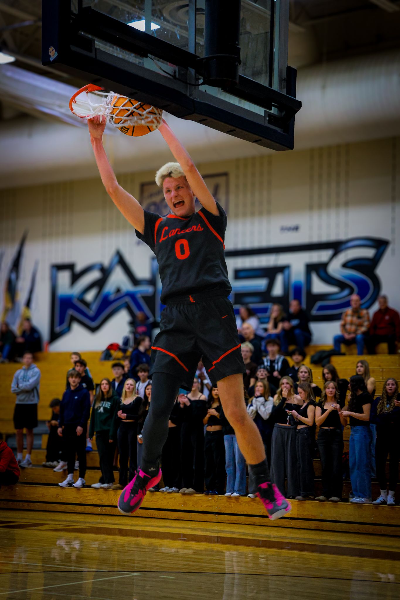 Basketball player soars through the air to perform a powerful slam dunk during an indoor game.