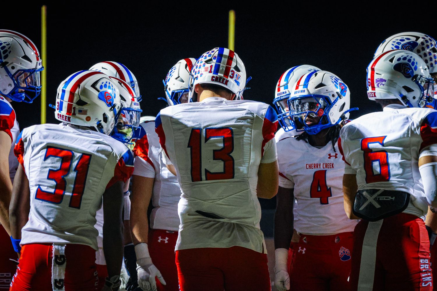 Football players in red, white and blue uniforms line up on the field during a game.