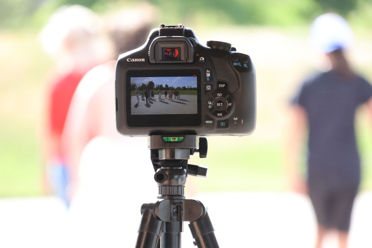 DSLR camera mounted on tripod capturing outdoor scene.