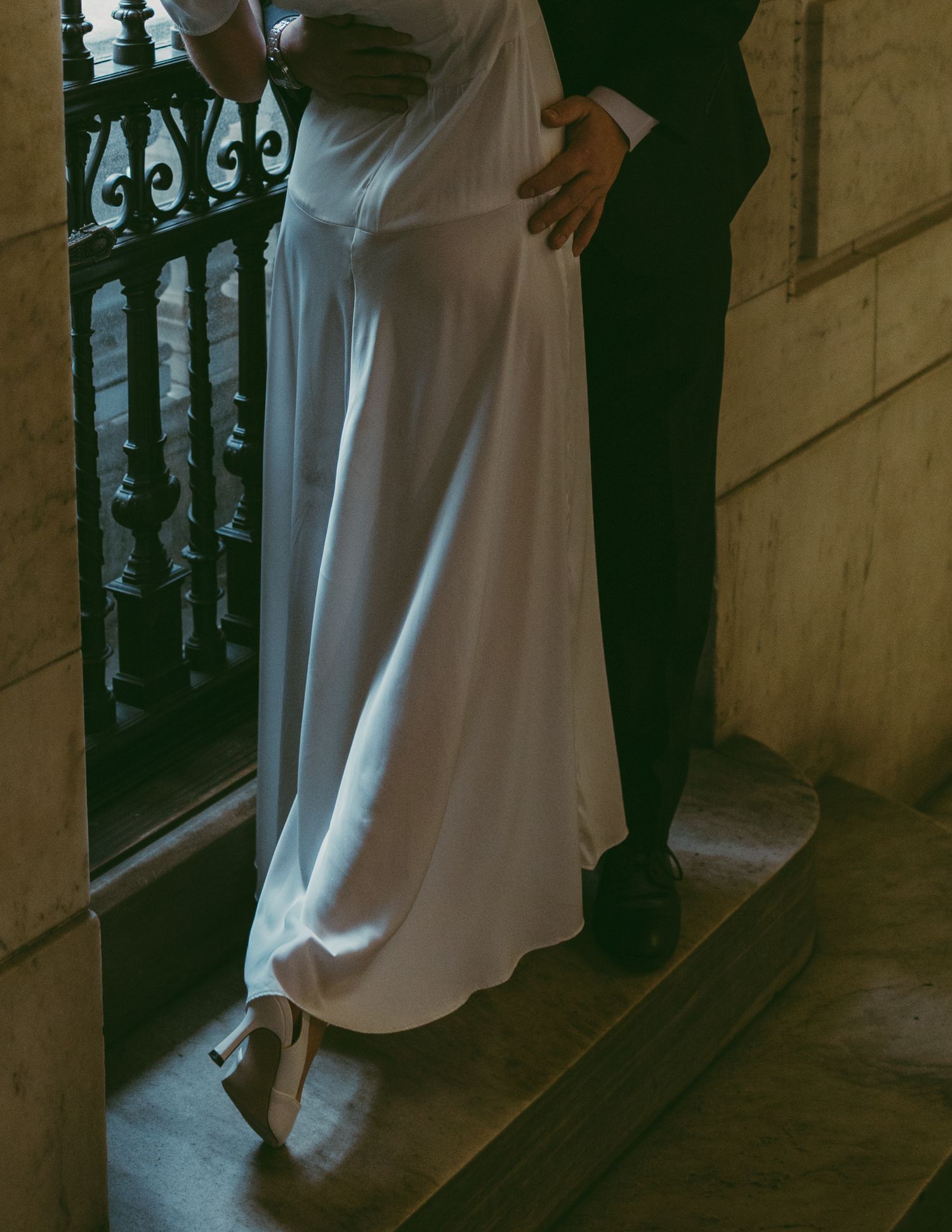 Couple in black and white attire posing by decorative railing.
