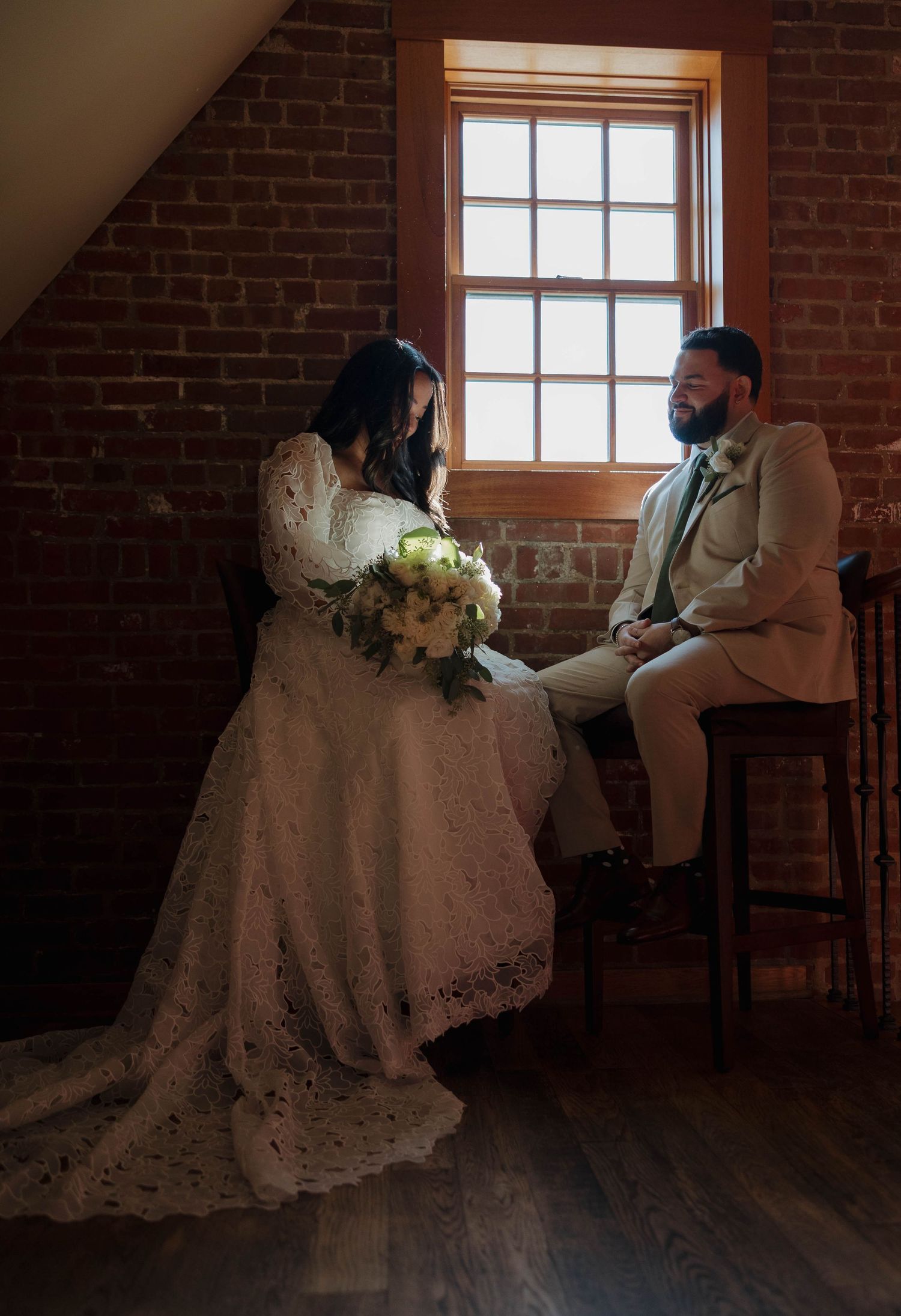 Wedding scene in rustic brick room with natural window lighting.