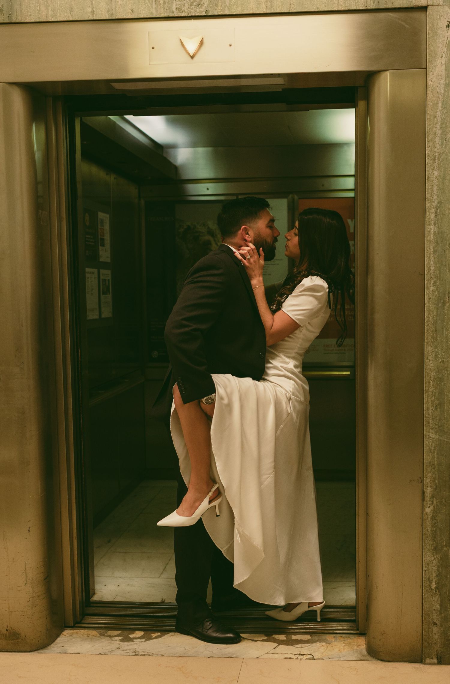 A romantic couple shares an intimate moment in a dimly lit hallway.