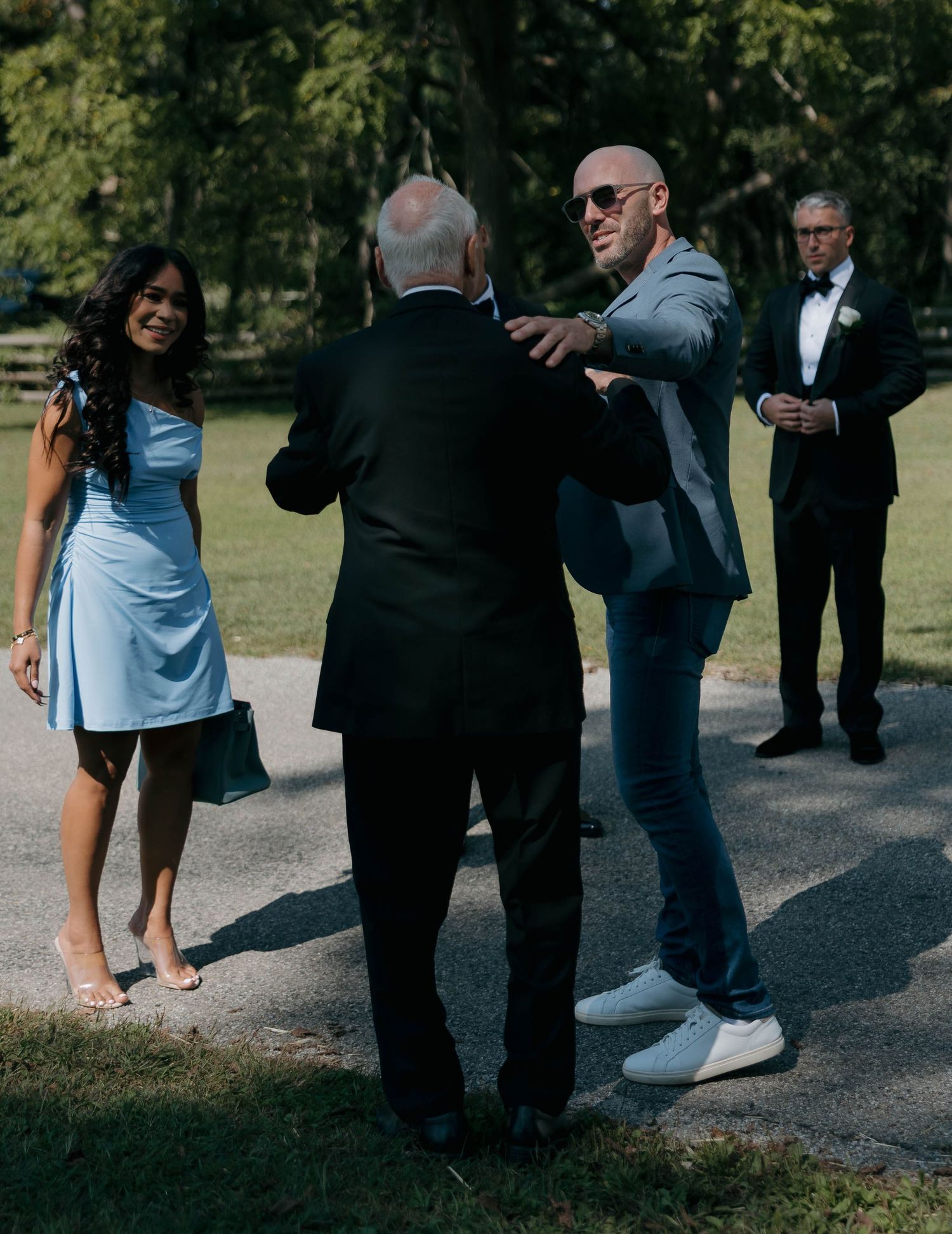 Wedding guests interacting outdoors on a sunny day during a casual moment.