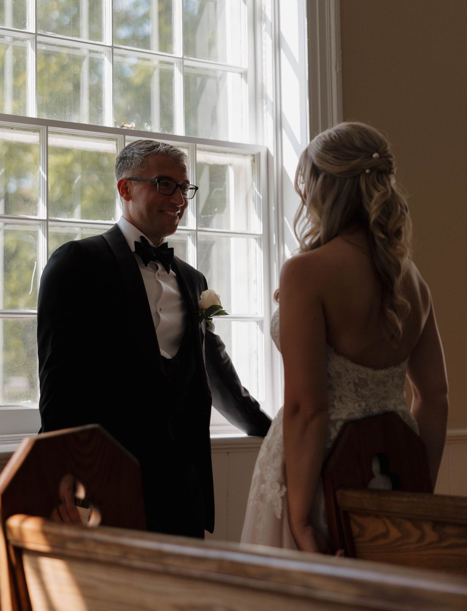 A couple shares an intimate moment by sunlit windows during their wedding ceremony.