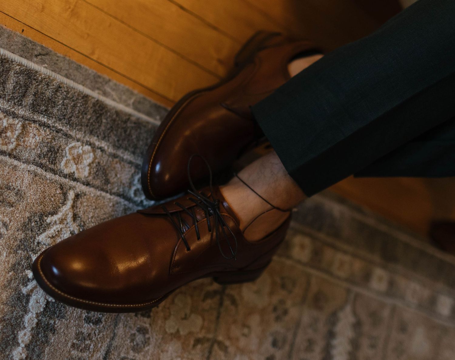 Detail shot of polished dress shoes on rustic brick surface at wedding.