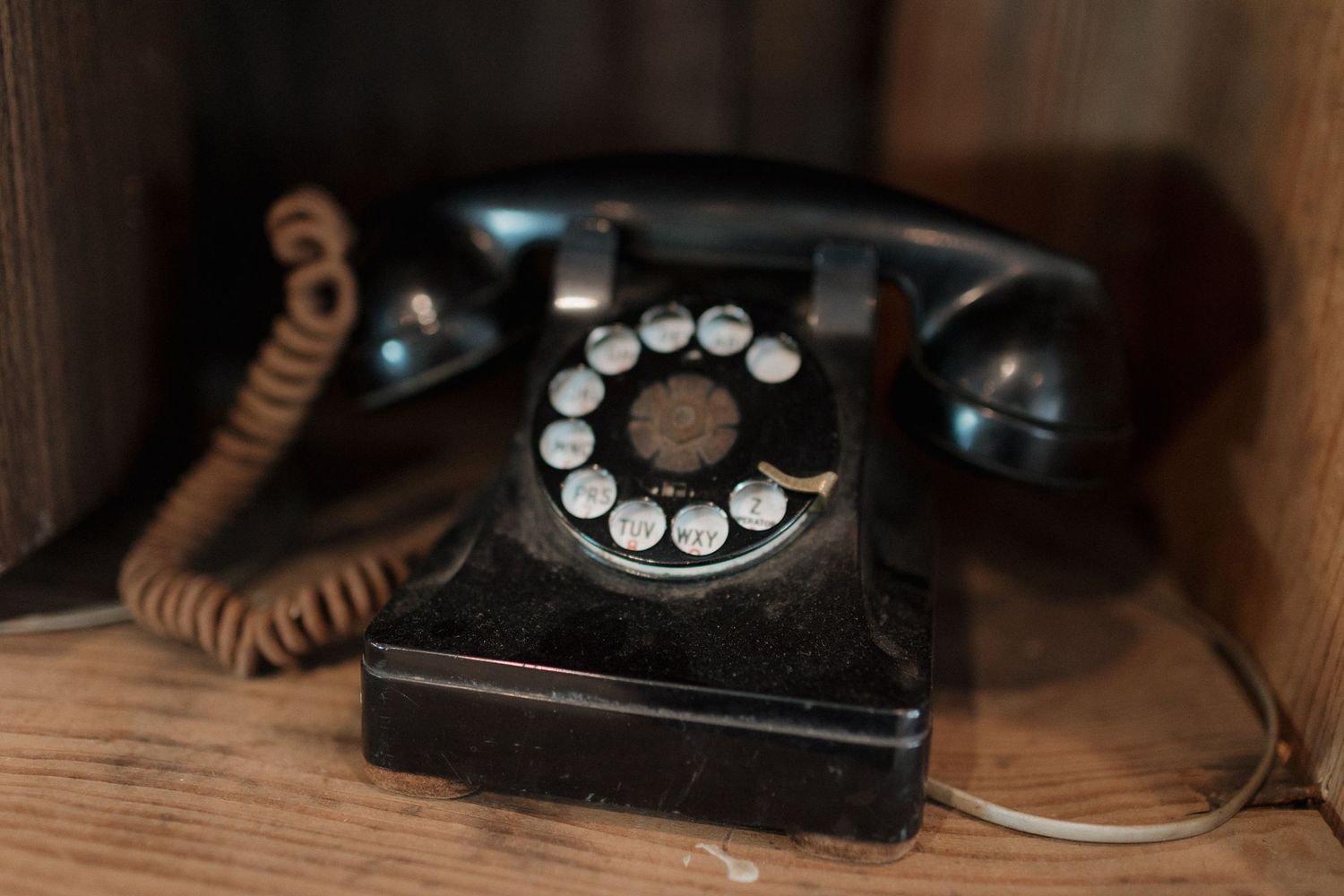 Collection of vintage rotary telephones displayed on wooden surface.