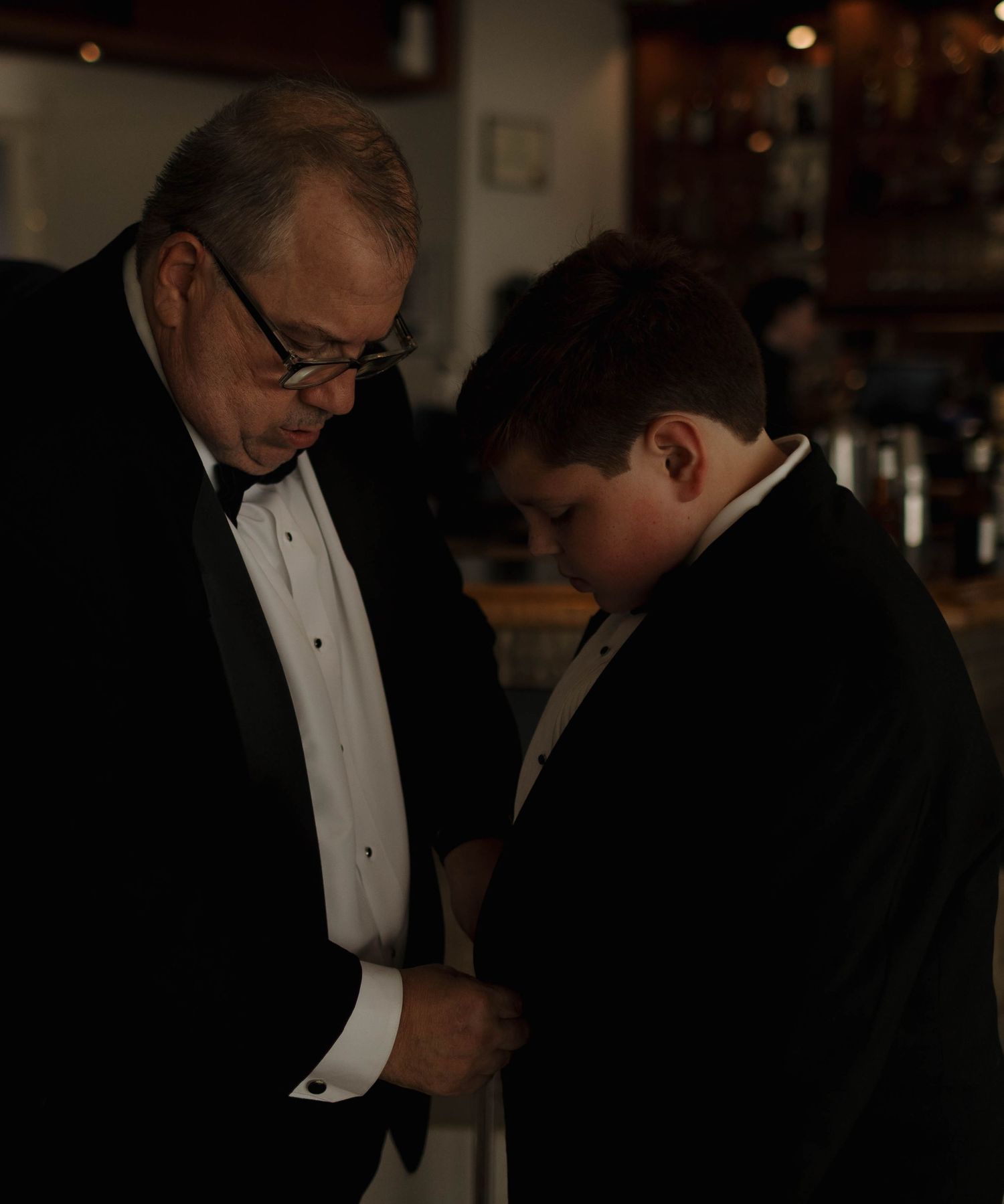 Men in tuxedos and bow ties preparing for formal event.