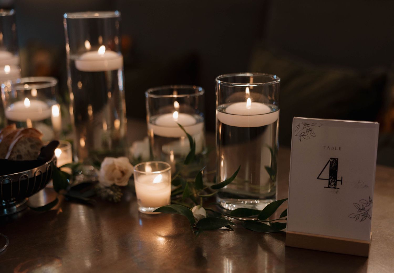 Romantic candlelit table setting with glass votives and table number four.