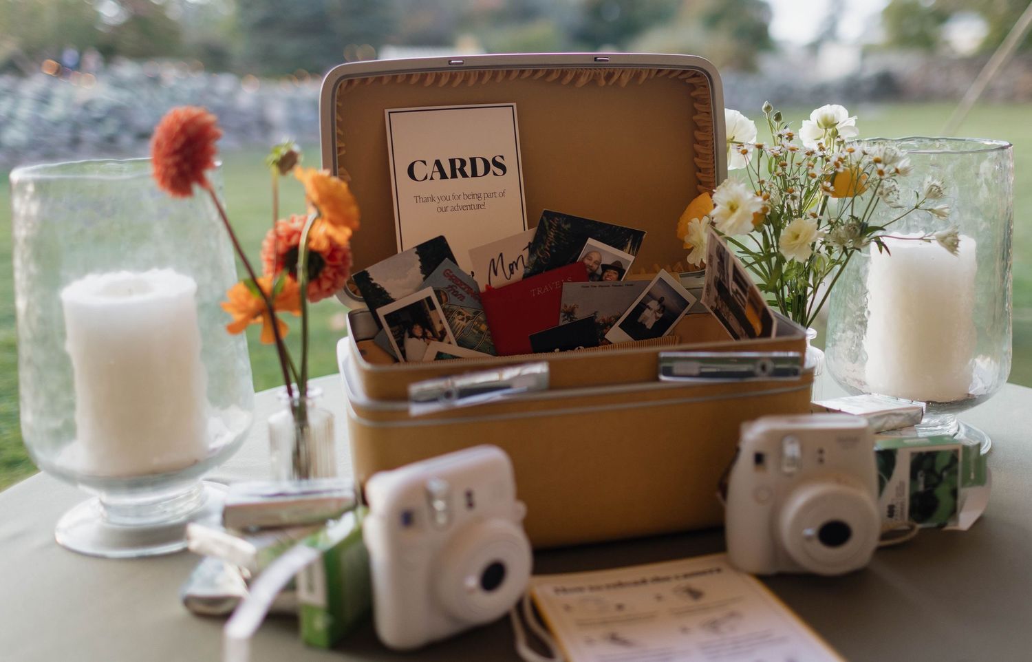 Vintage suitcase filled with cameras and photography equipment alongside flowers and candles.