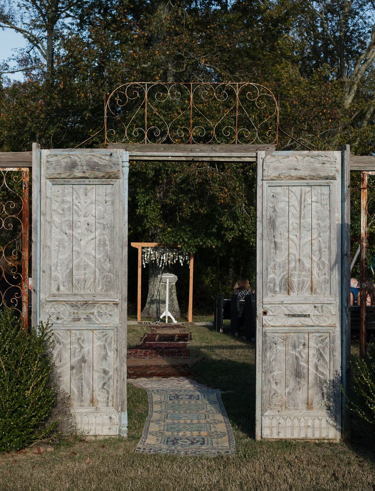 Vintage white doors arranged in an outdoor setting creating a rustic wedding backdrop.