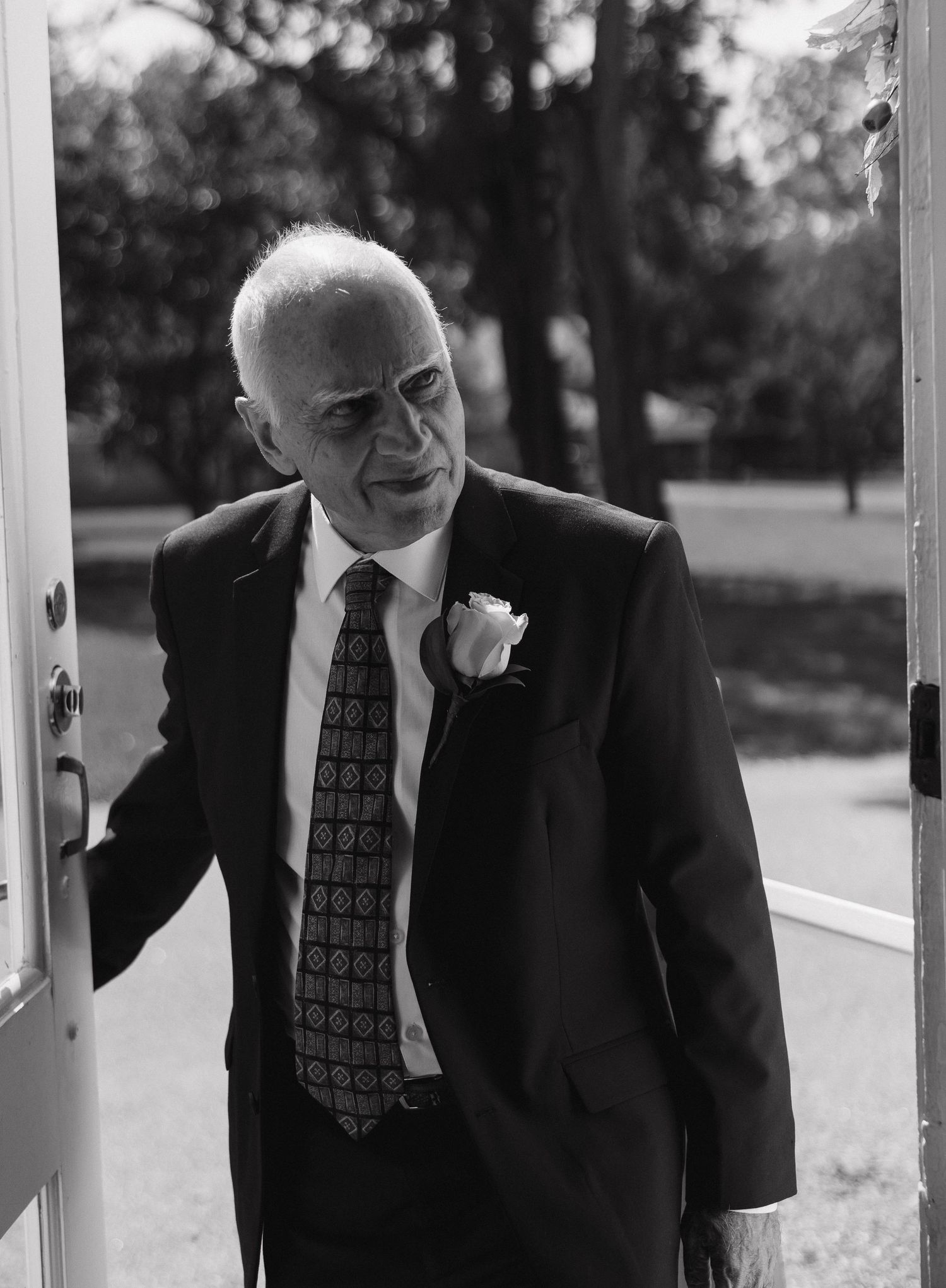 Formal-dressed guests interact and smile on an outdoor porch.
