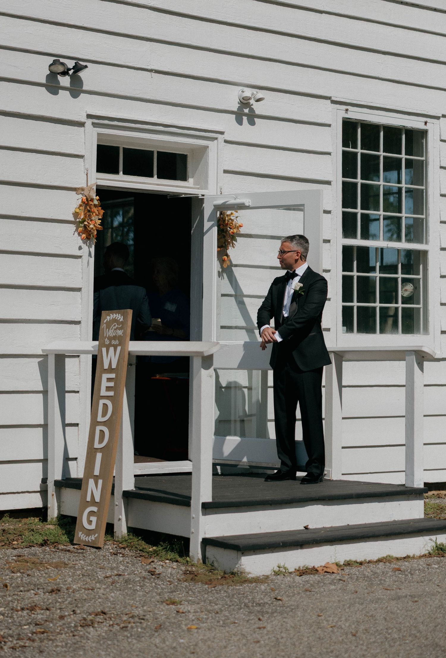 Decorative wooden signs spelling out 'WEDDING' line the entrance of a white building.