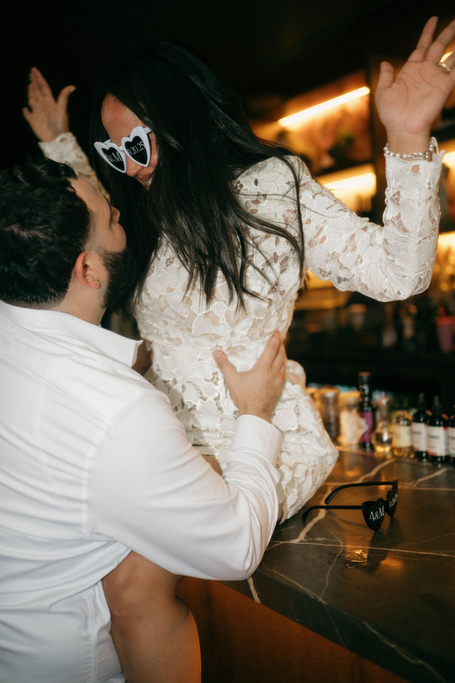 Candid dance moment captured at a bar with dramatic lighting and lace dress details.