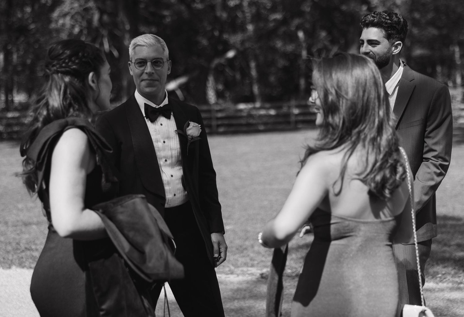 Groomsmen and wedding party members share laughter and candid moments at an outdoor venue.