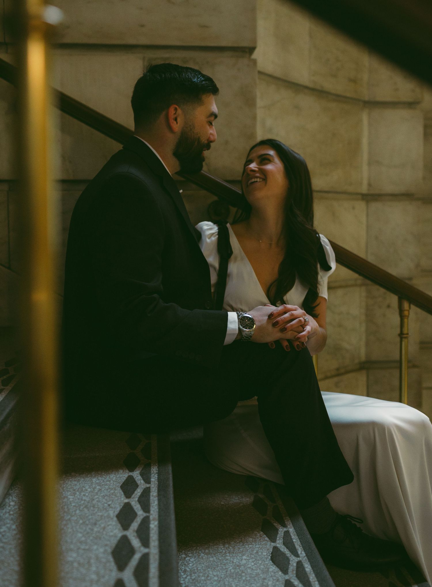 Couple sharing intimate moment on ornate stone staircase.