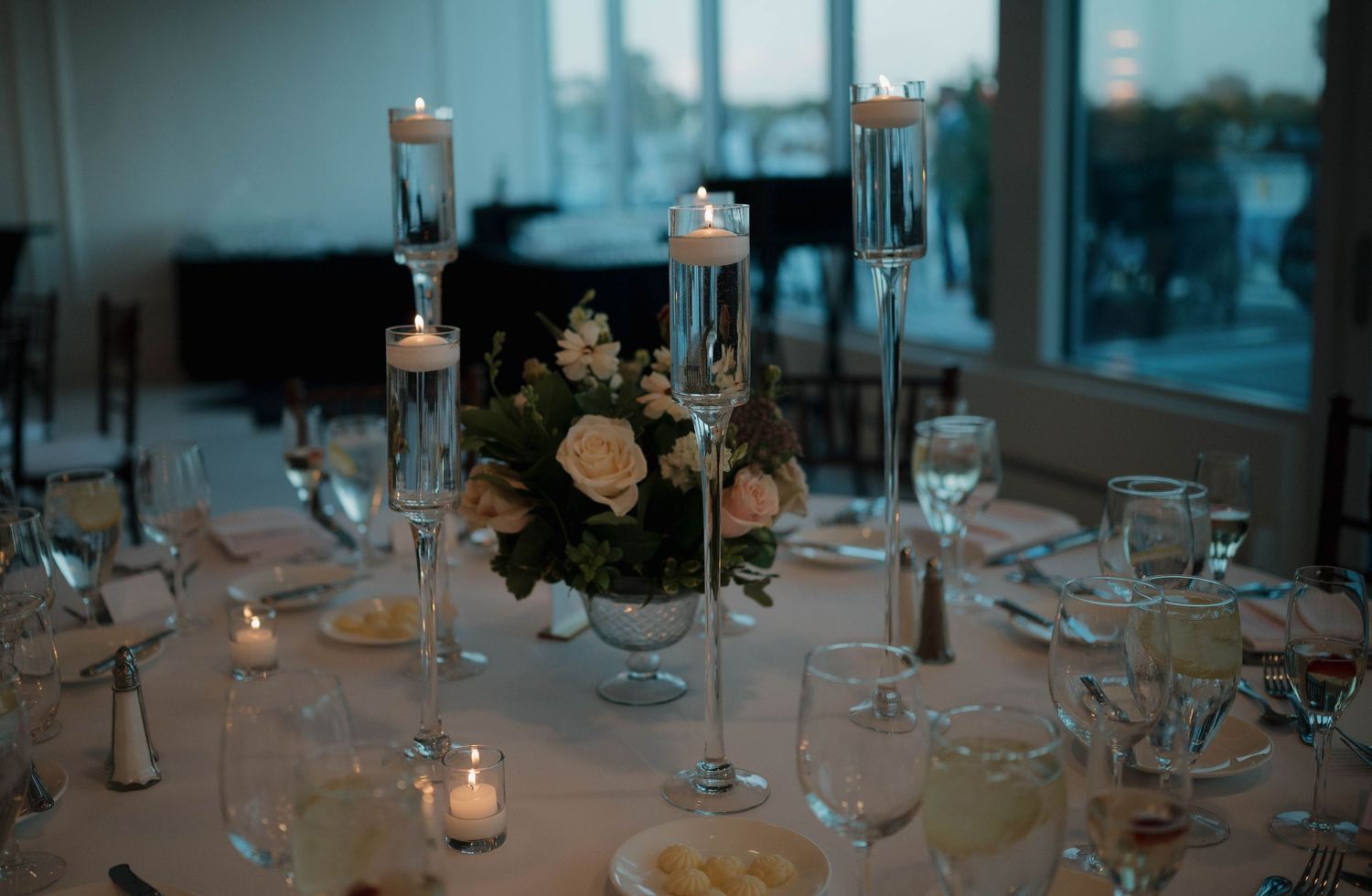 Elegant wedding reception table setting with tall candlesticks and floral centerpieces.