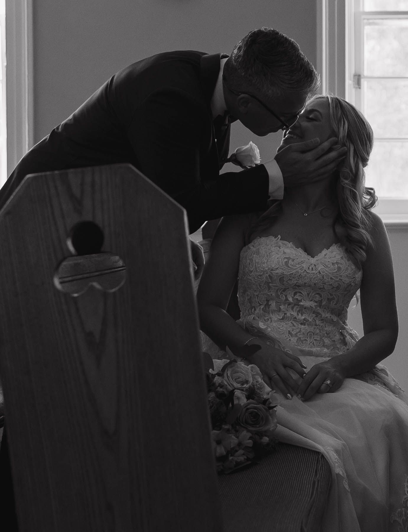 A black and white romantic wedding photo showing a tender moment in church.