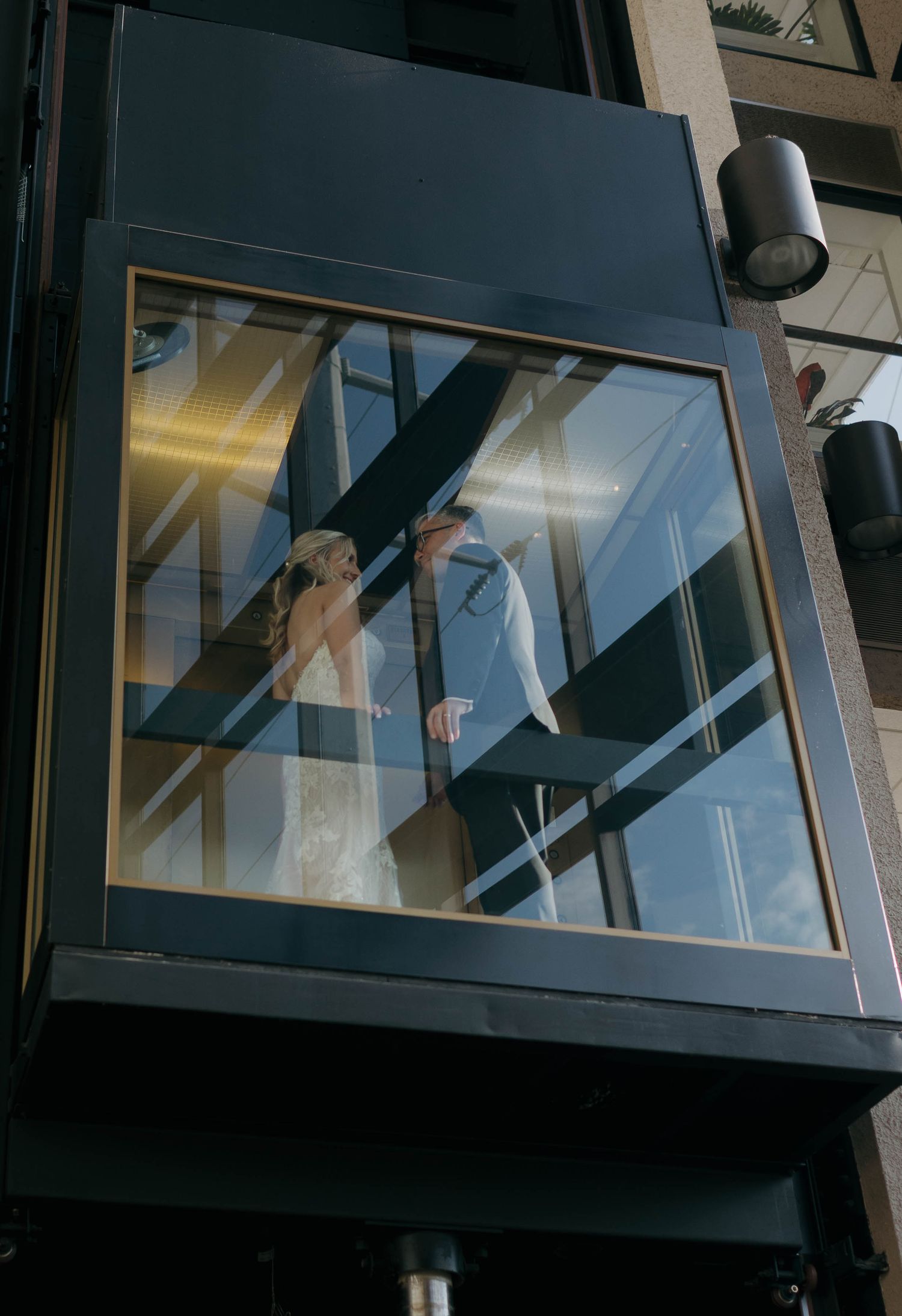 Modern glass elevator with reflective surfaces and lighting creates an architectural composition.