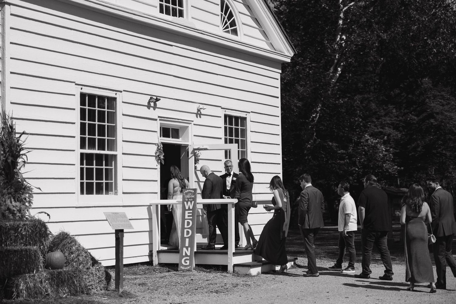 White clapboard church exterior with multiple windows and guests gathering outside.