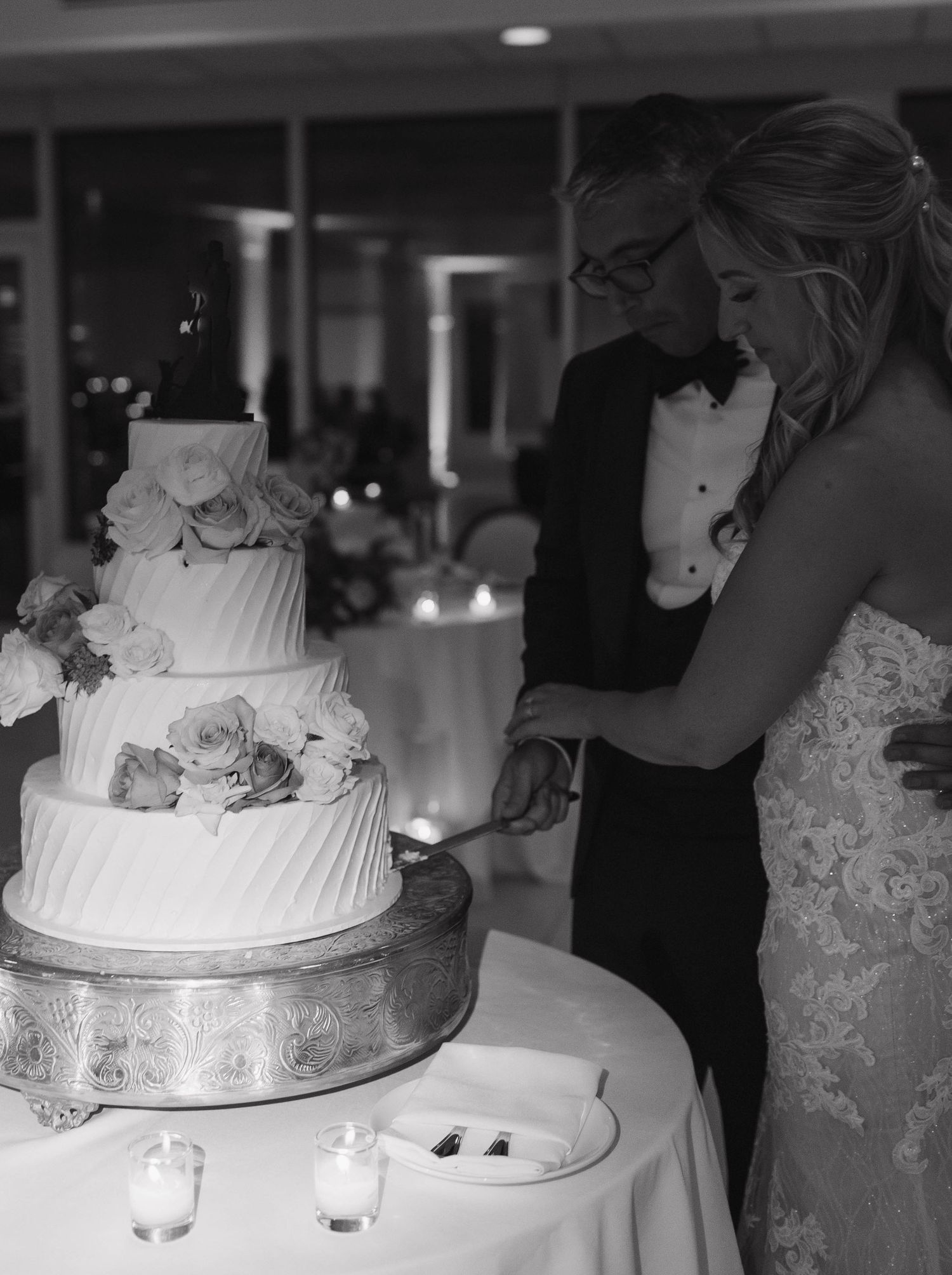 Newlyweds cut their elegant white tiered wedding cake together at reception.