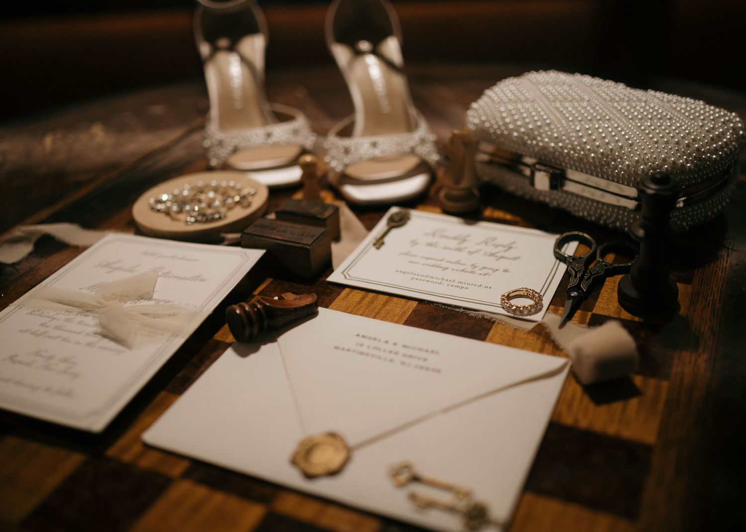 Wedding details including invitations, shoes, and accessories arranged on a rustic wooden surface.