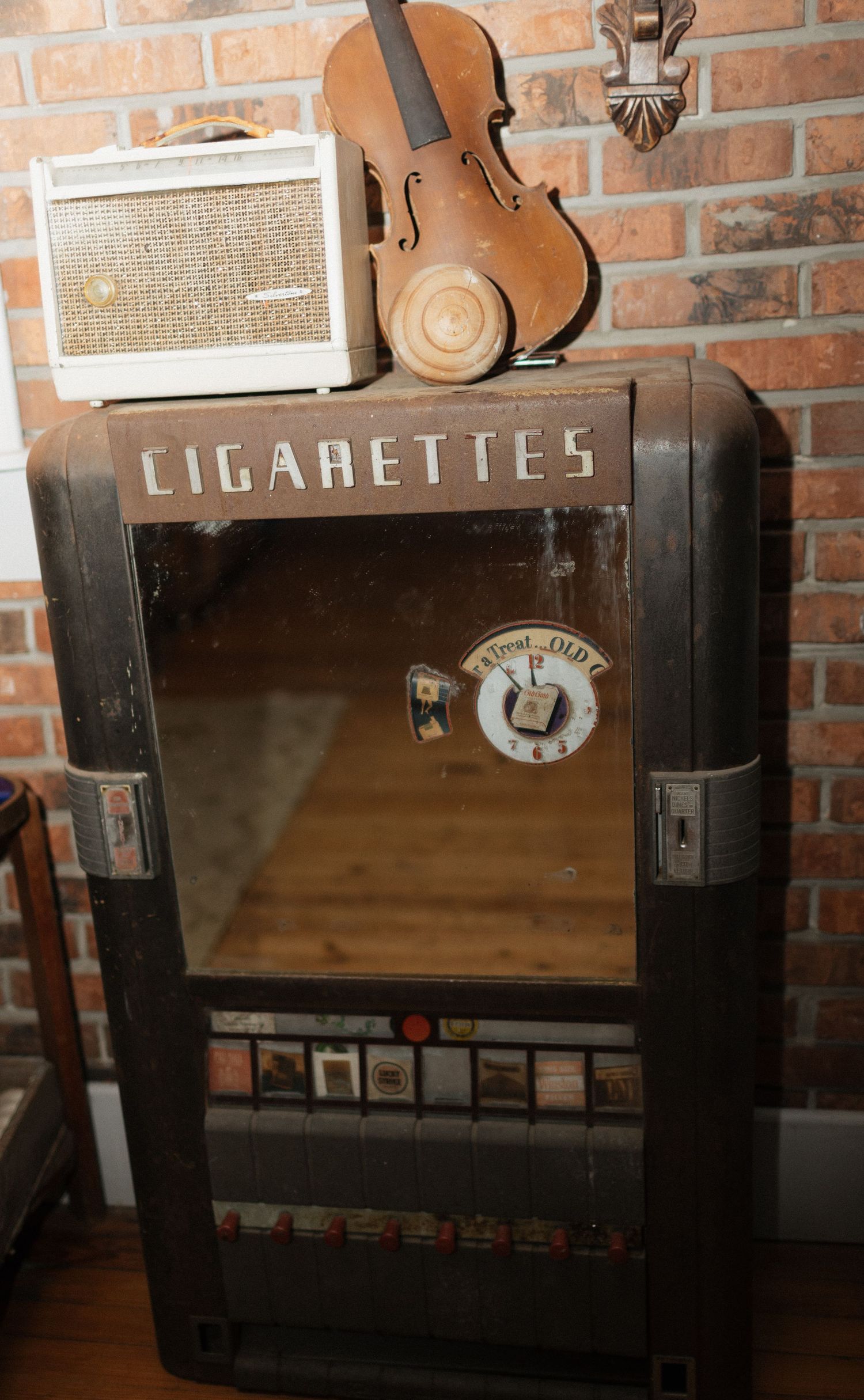 Vintage cigarette vending machine with brick wall background.