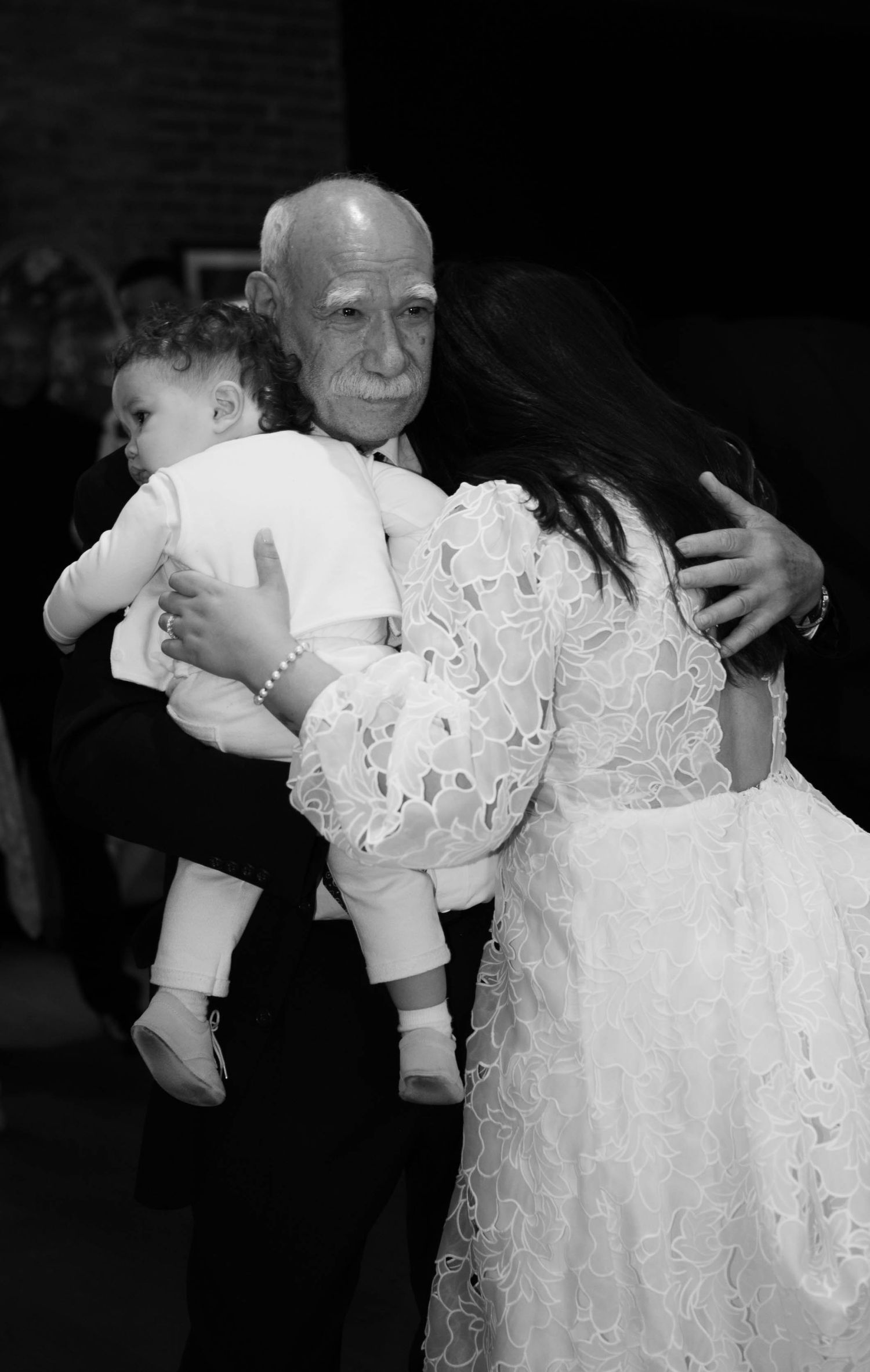 A tender moment during a wedding reception with a lace dress and formal attire.