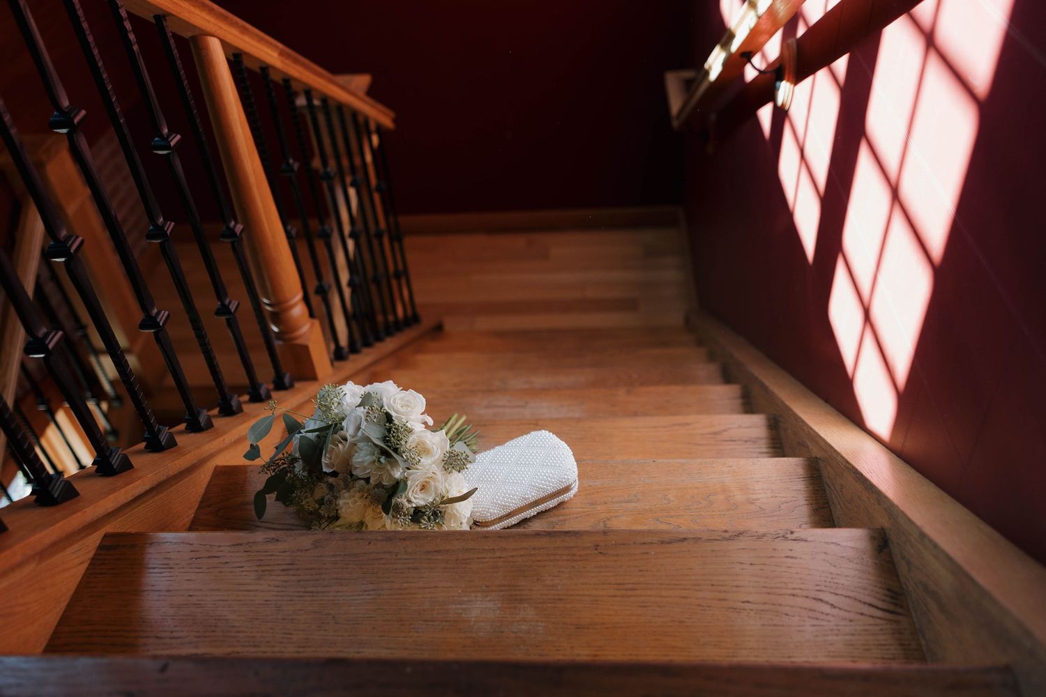 Dramatic shadows from window light fall across a wooden staircase in an interior space.