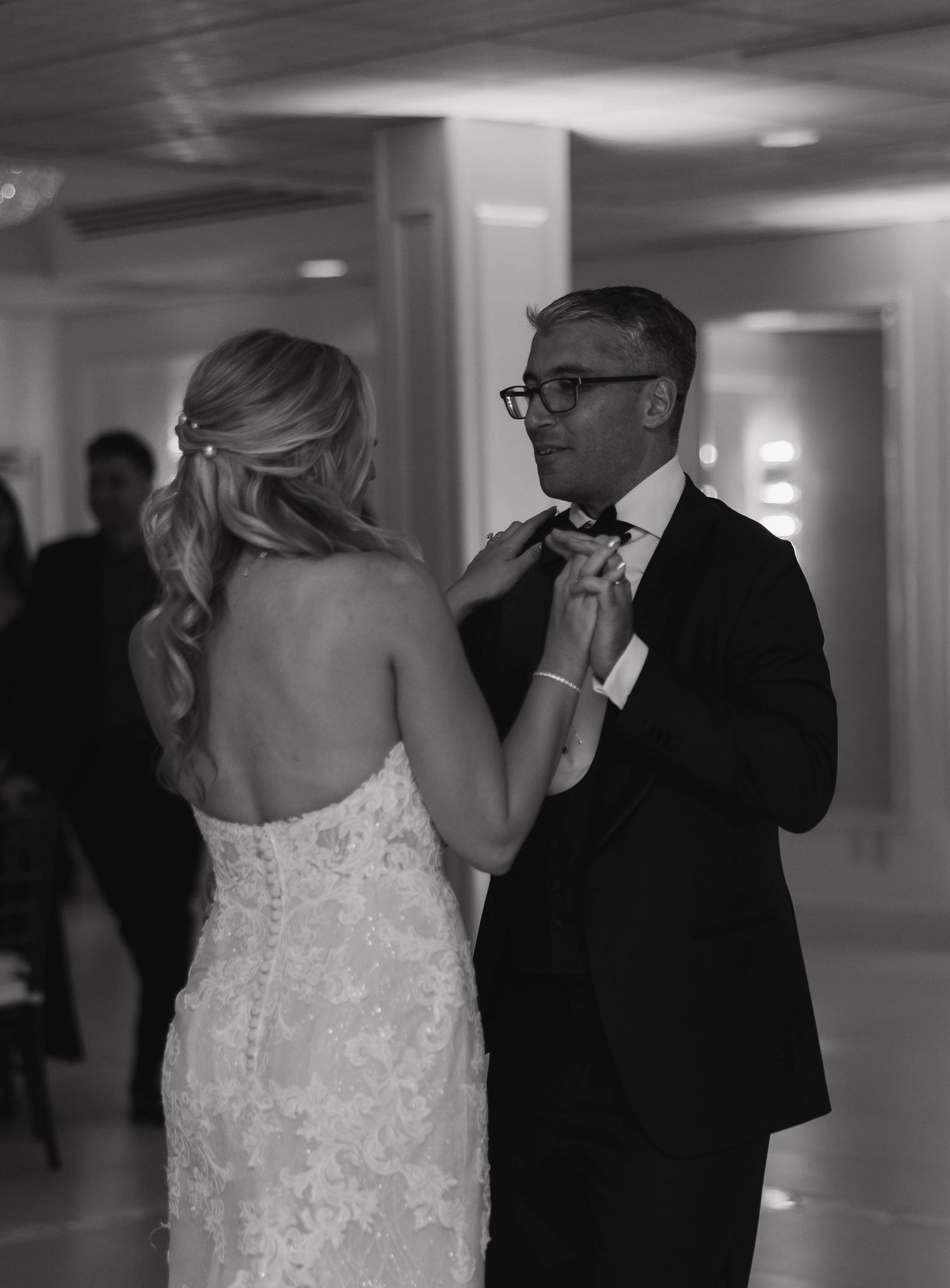 Couple shares intimate dance at wedding reception in formal attire.