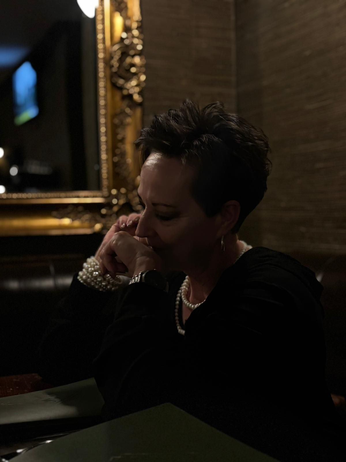 A dimly lit interior scene with ornate gold-framed mirrors on the wall.