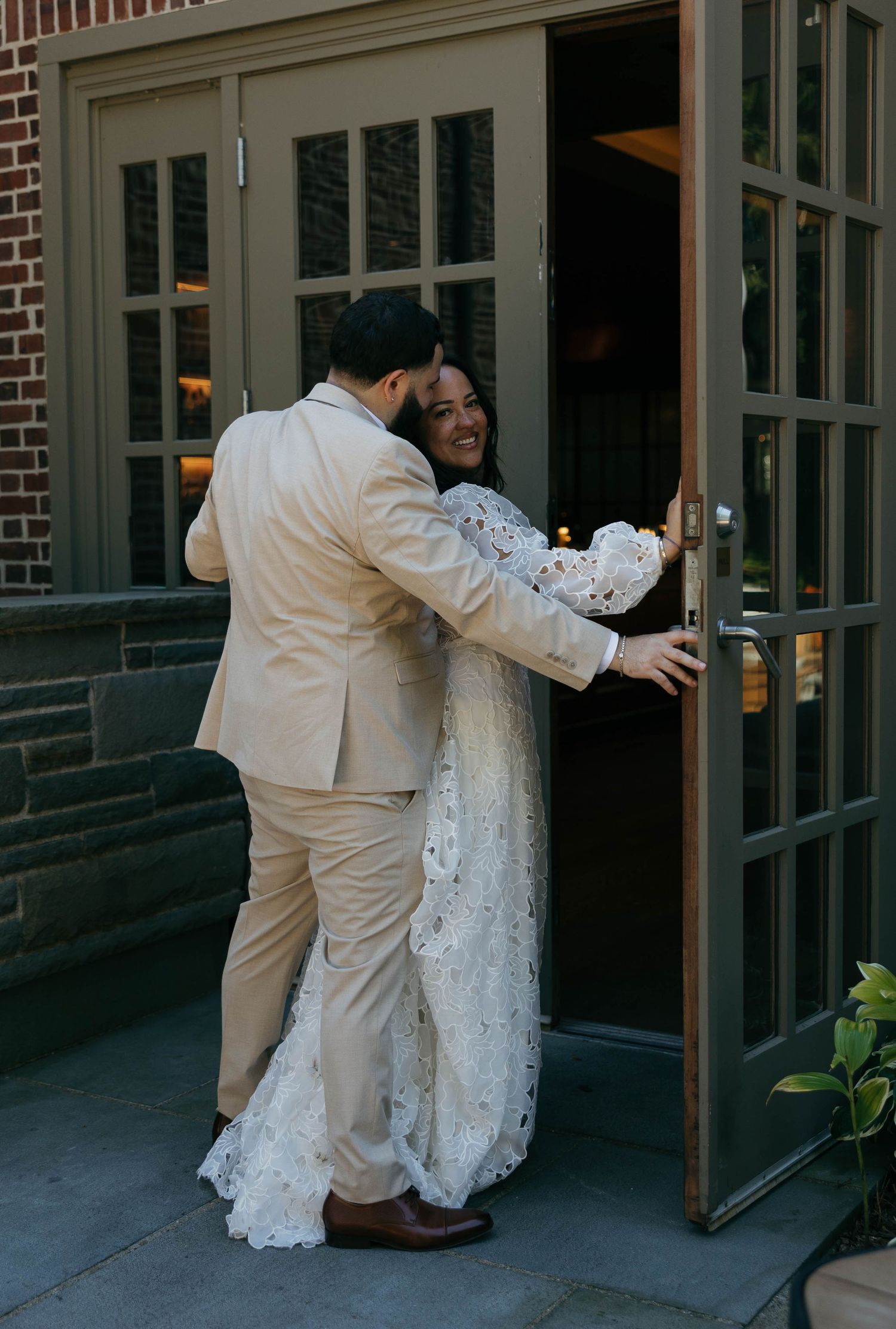A joyful wedding moment captured as the couple shares a laugh by the entrance doors.