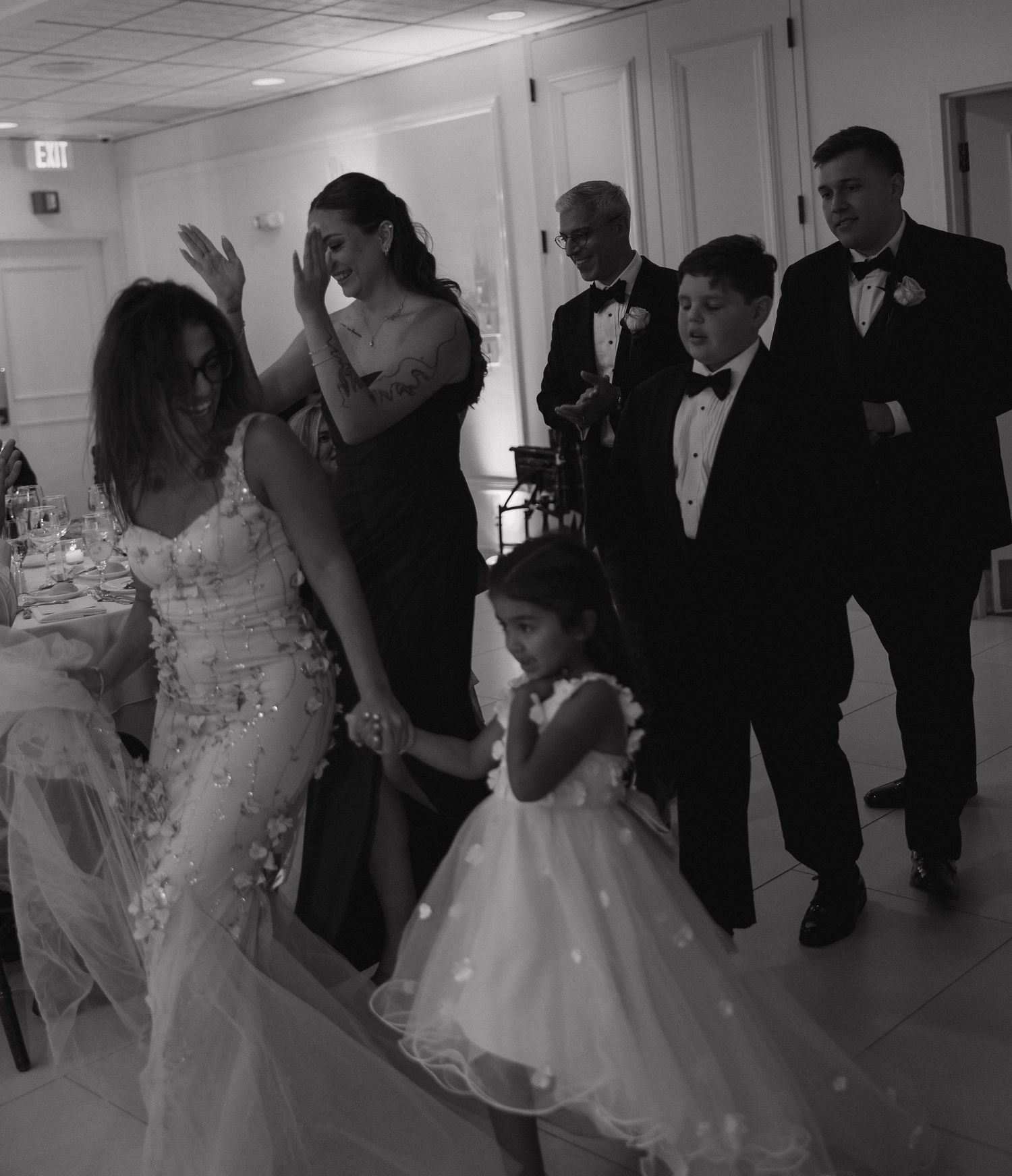 Wedding party and young flower girl in formal attire at reception venue.