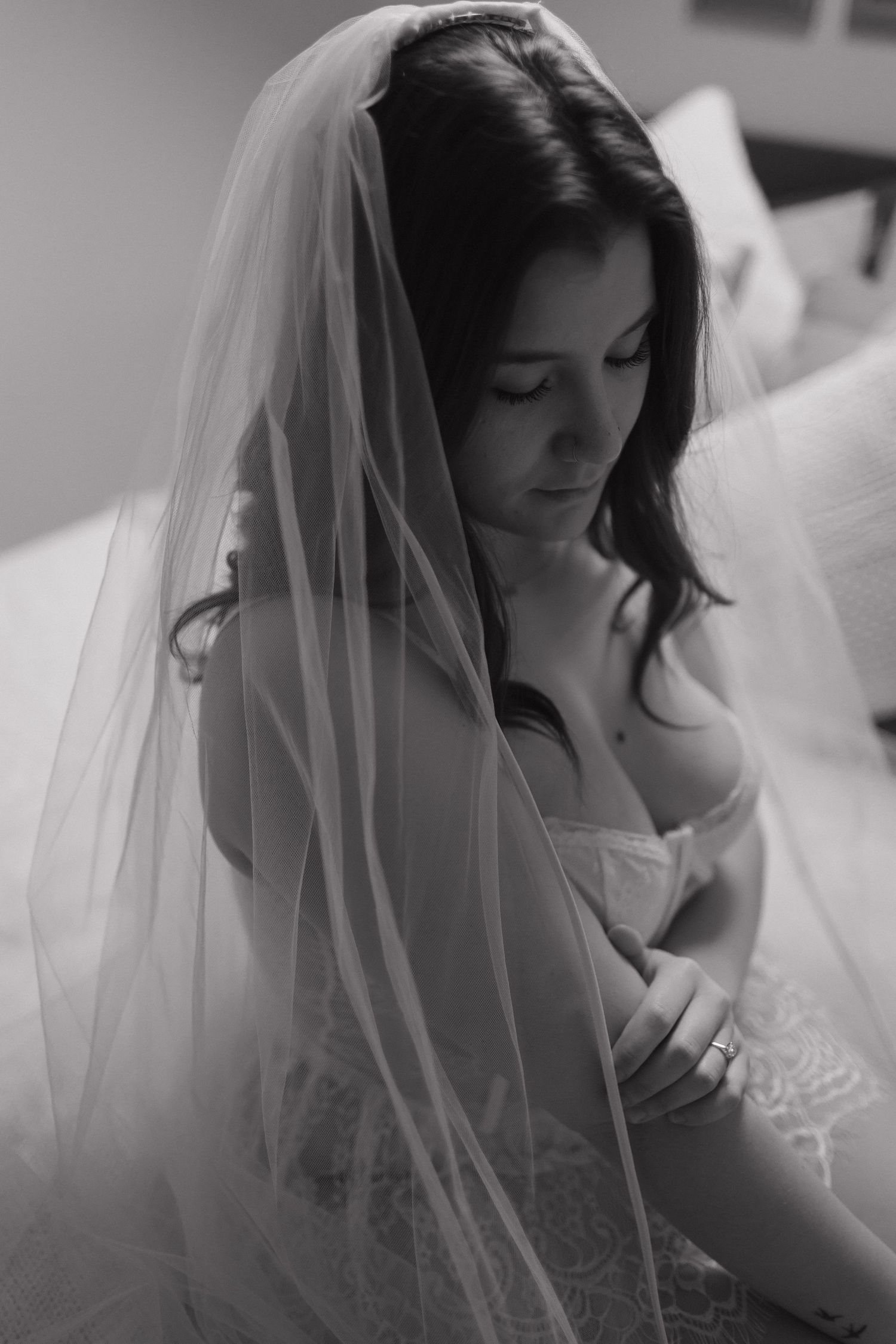Black and white portrait of a bride in a delicate veil and strapless wedding dress looking down thoughtfully.