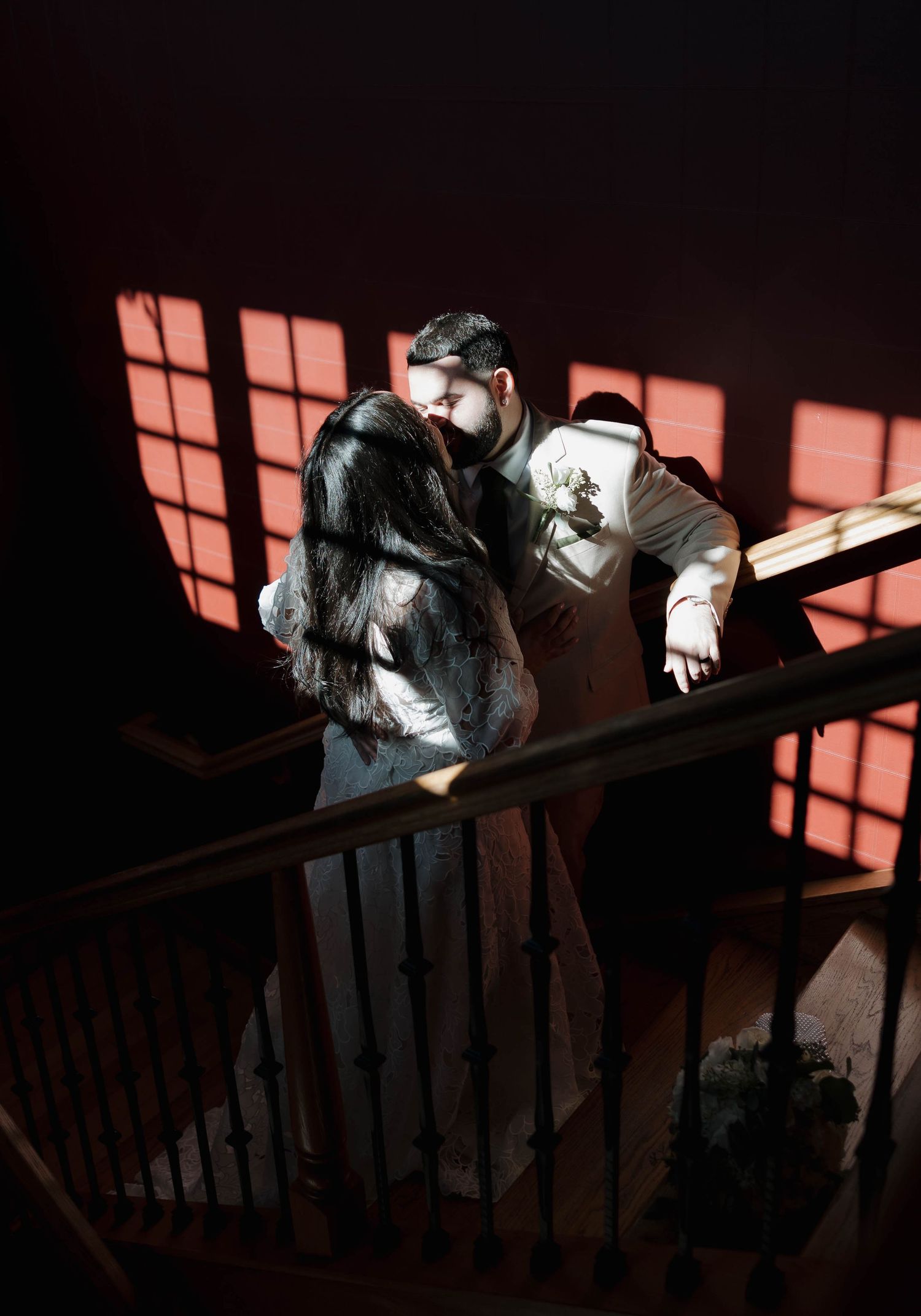 Sunlight streams through windows casting dramatic shadows on a dark staircase.