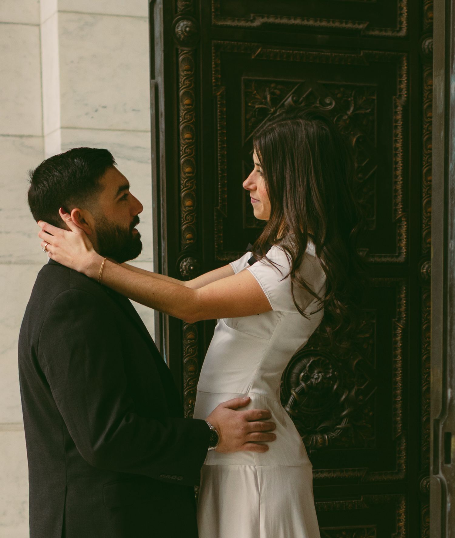 A couple in contrasting black and white outfits posing by a decorative doorway.