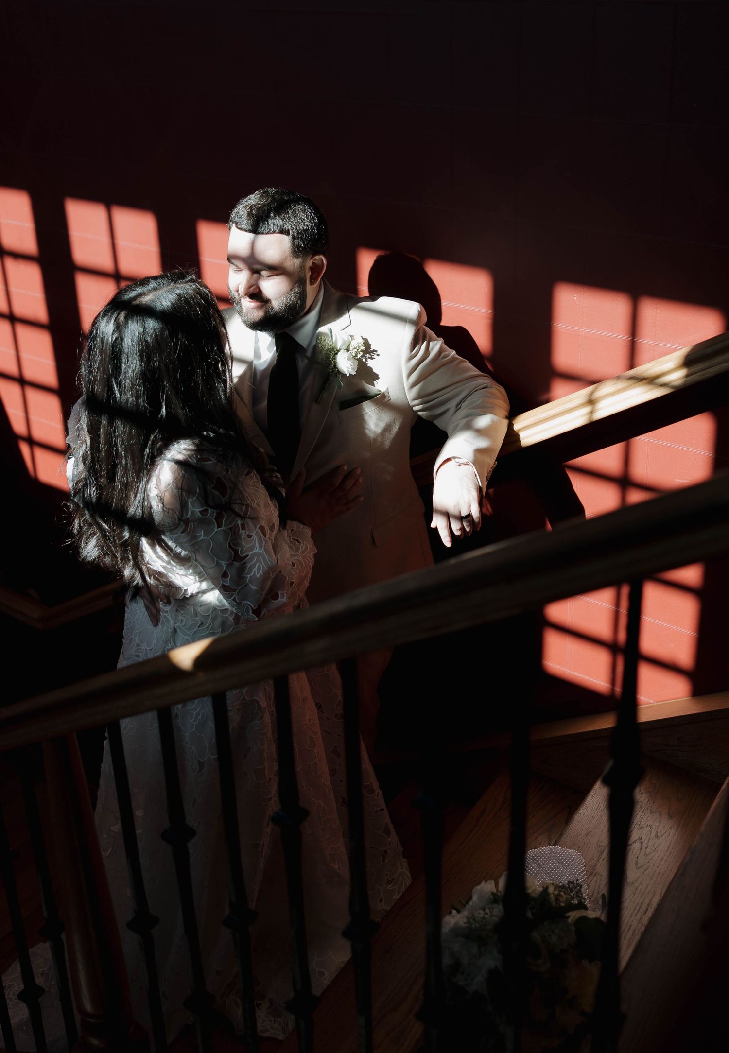 Dramatic window light creates contrasting shadows on a wooden banister and stairs.