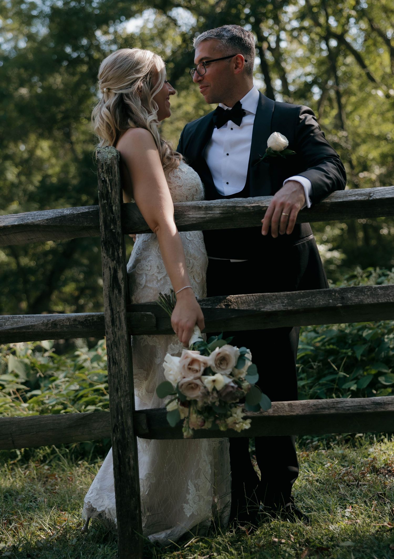 Wedding couple shares an intimate moment by a rustic wooden fence.