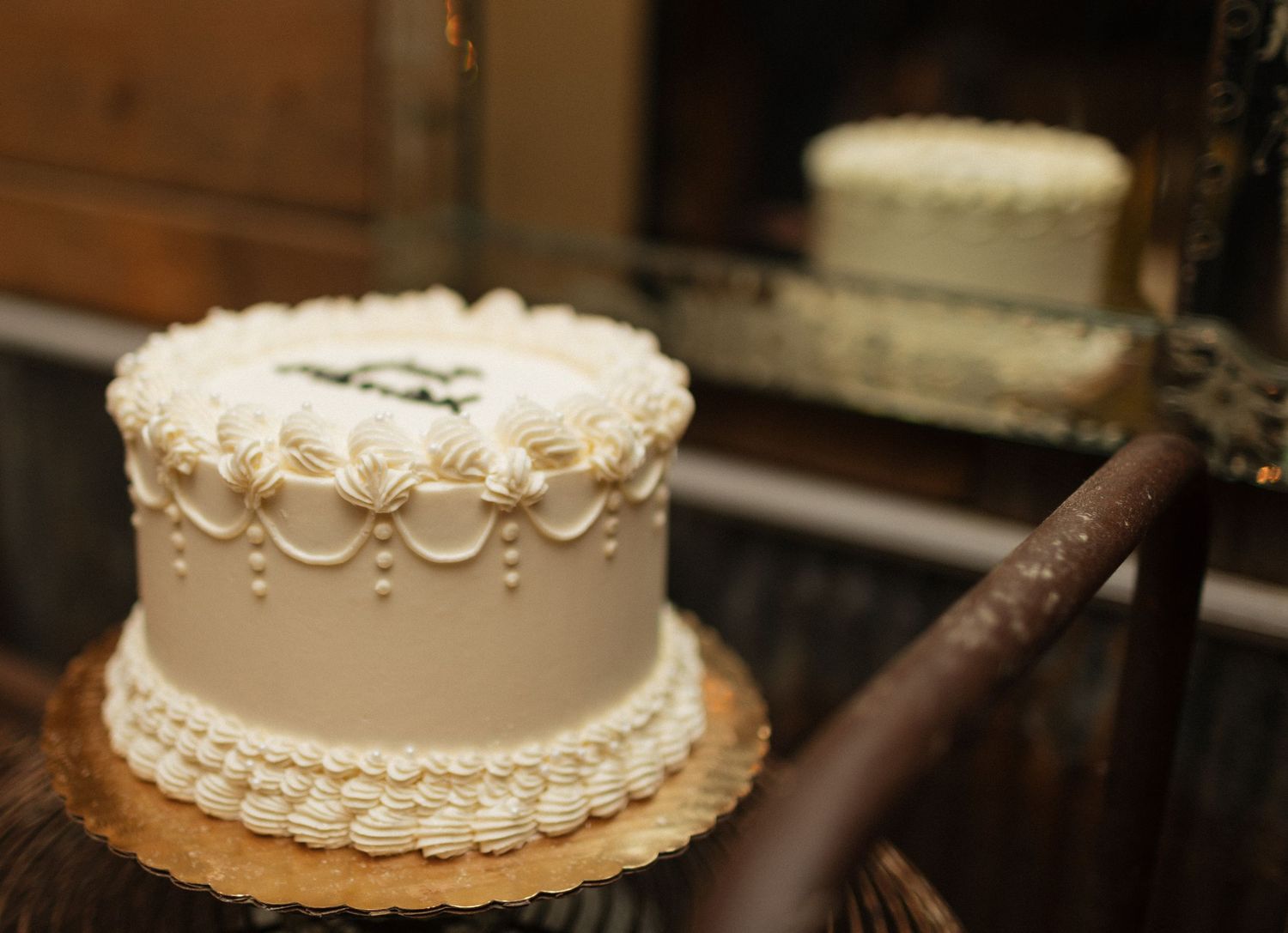 White wedding cake with delicate piped frosting details and pearl decorations.