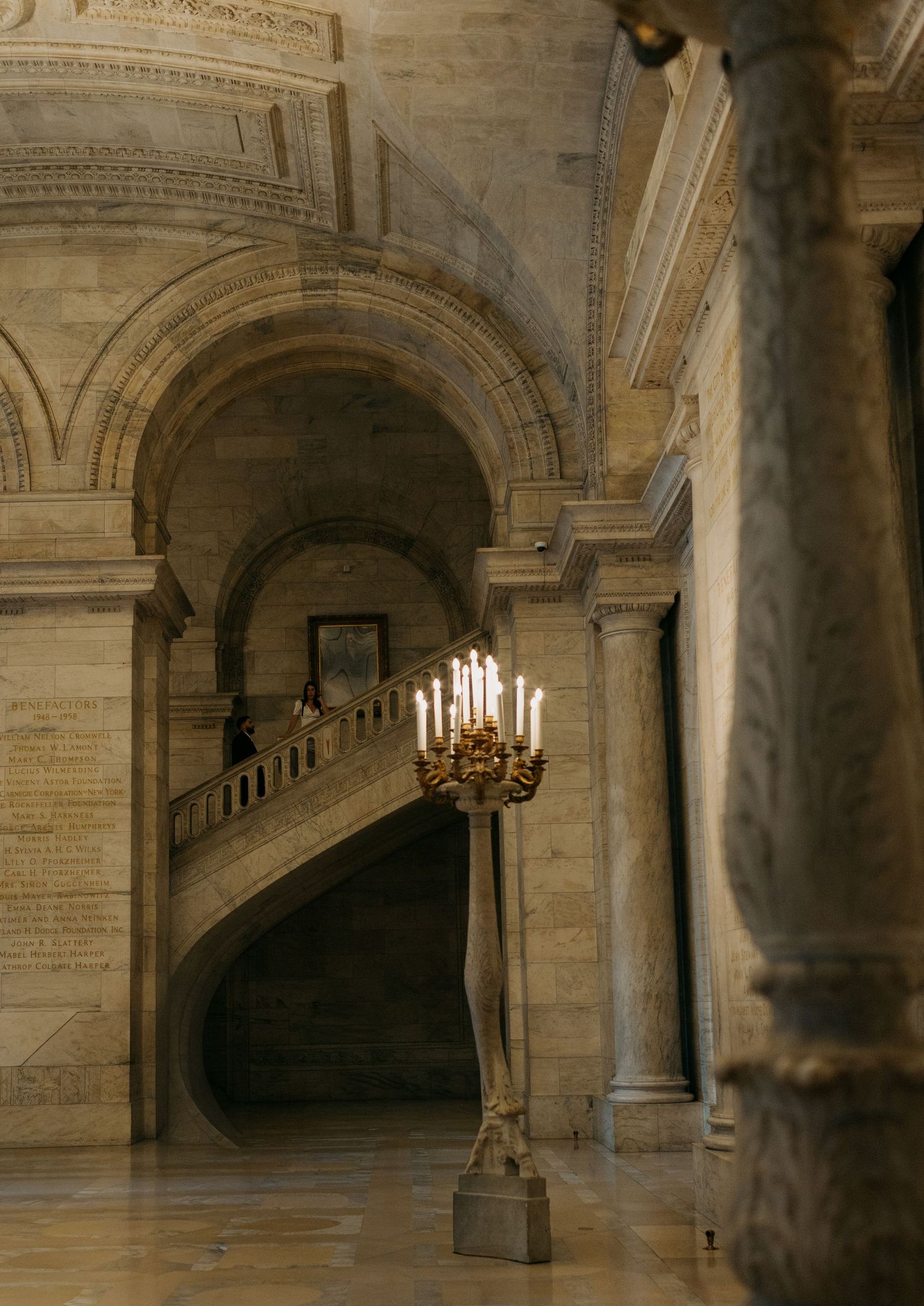 Historic stone archways and columns in a grand architectural space with candles.