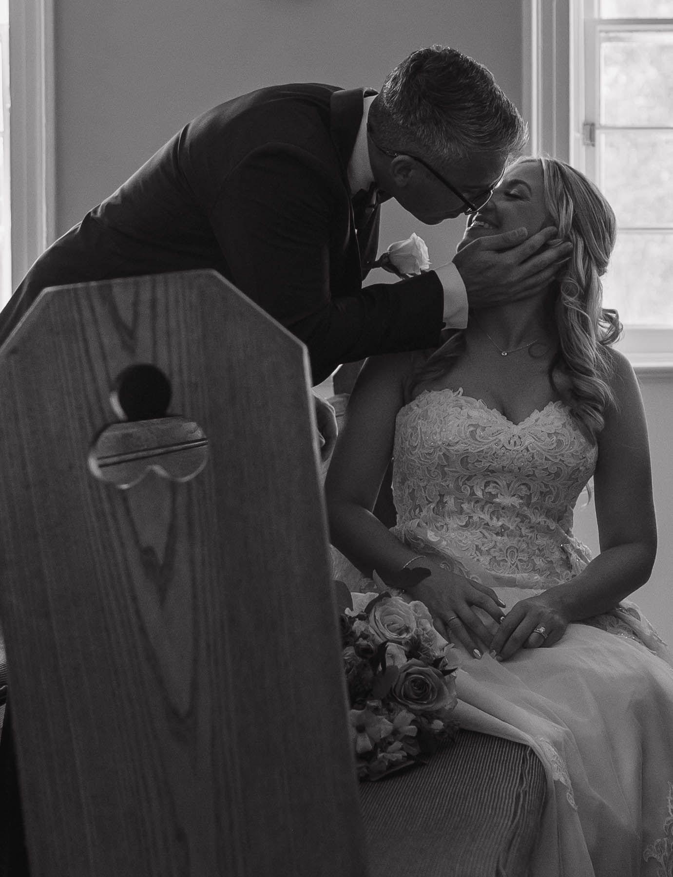 A romantic black and white wedding portrait showing a tender moment between newlyweds.