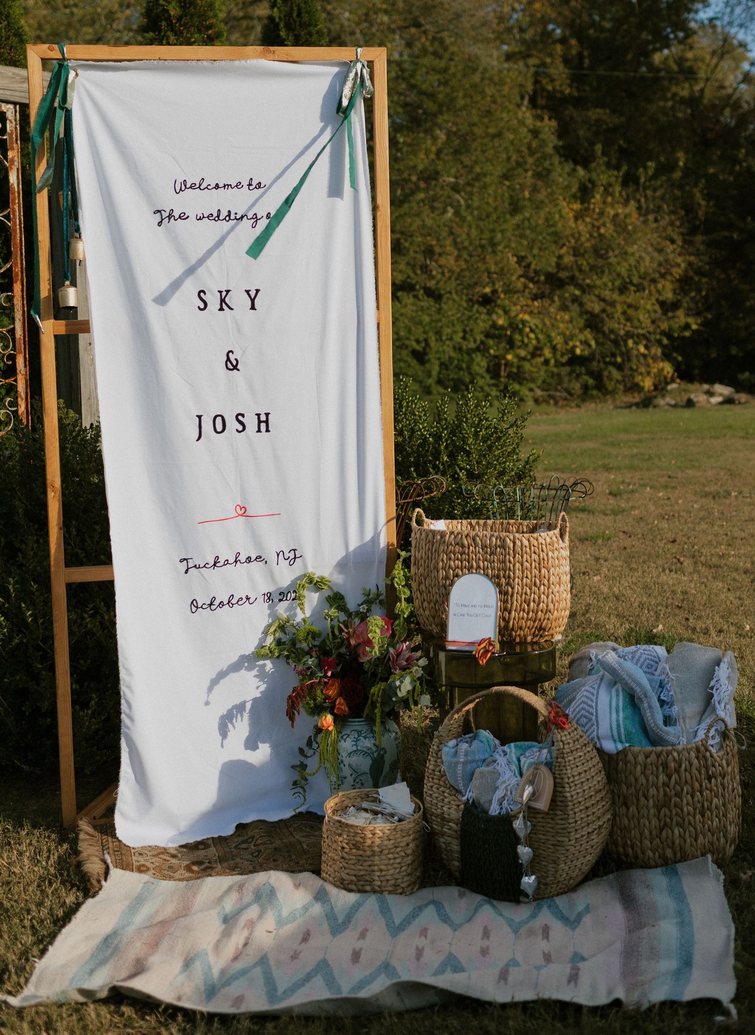 White fabric backdrop with text decorations and woven baskets arranged for an outdoor event setup.