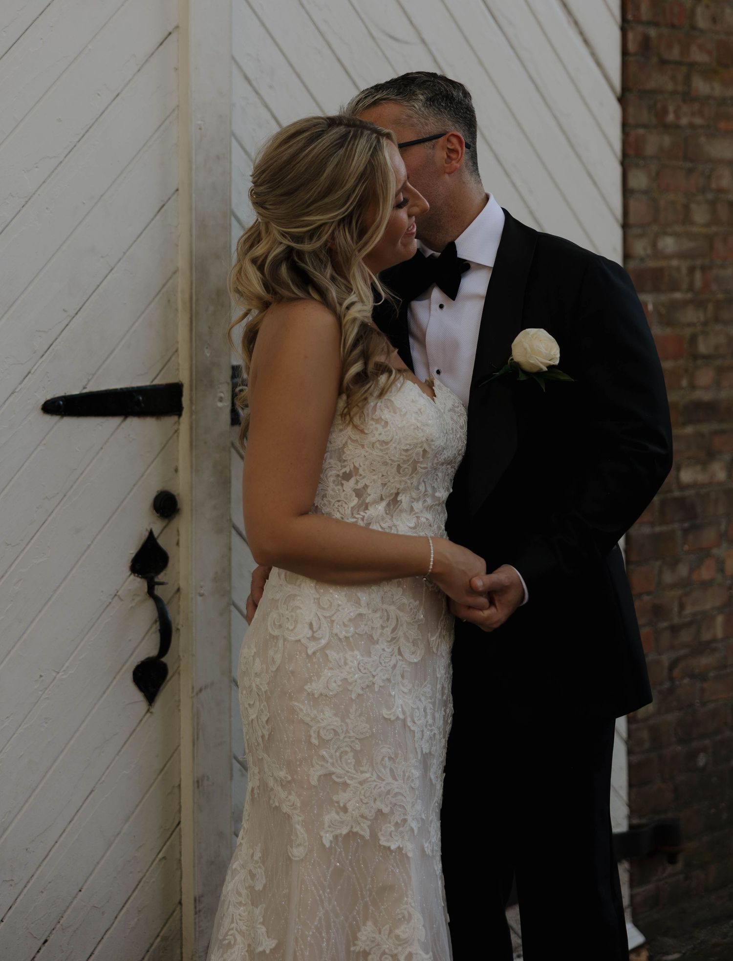 A romantic first look sequence between newlyweds by a white barn door.