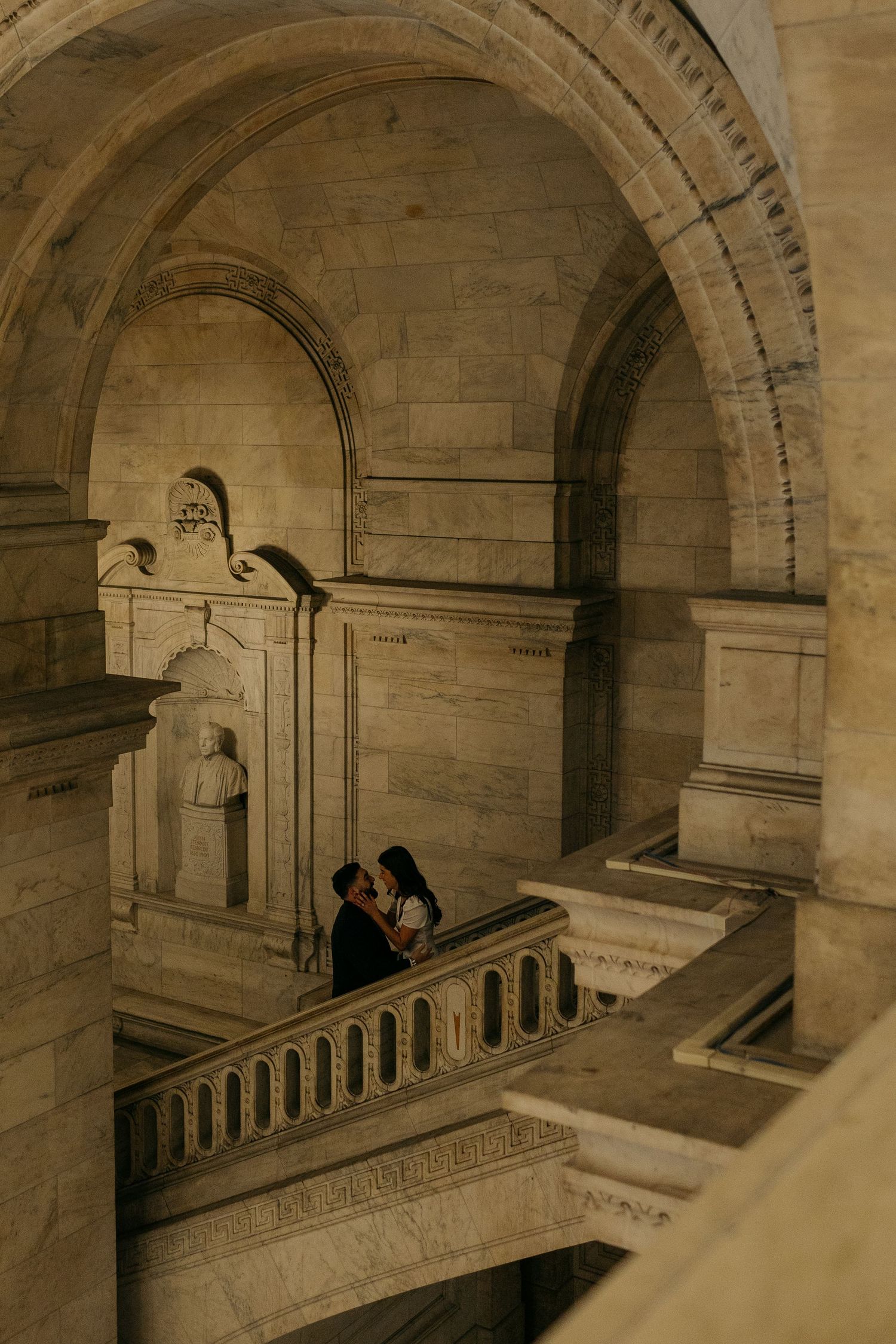 Series of stone arches and staircases in a classical building interior.