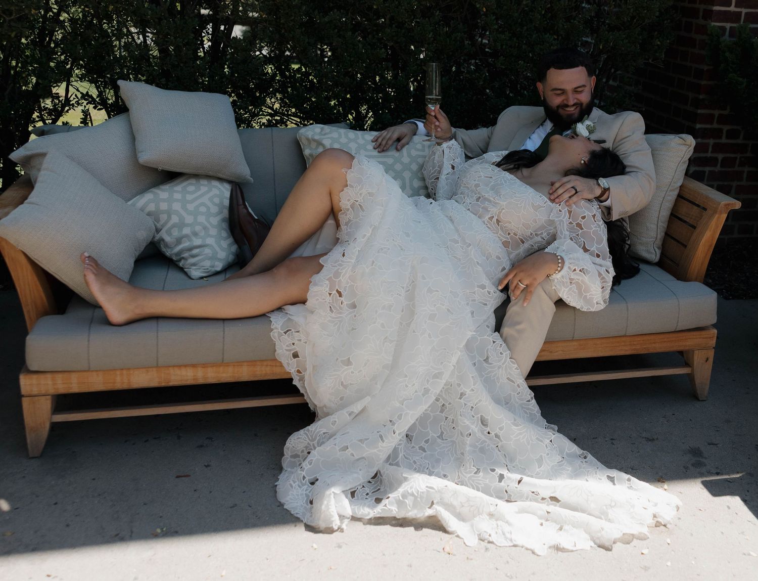 Wedding couple lounging on modern outdoor furniture during reception.